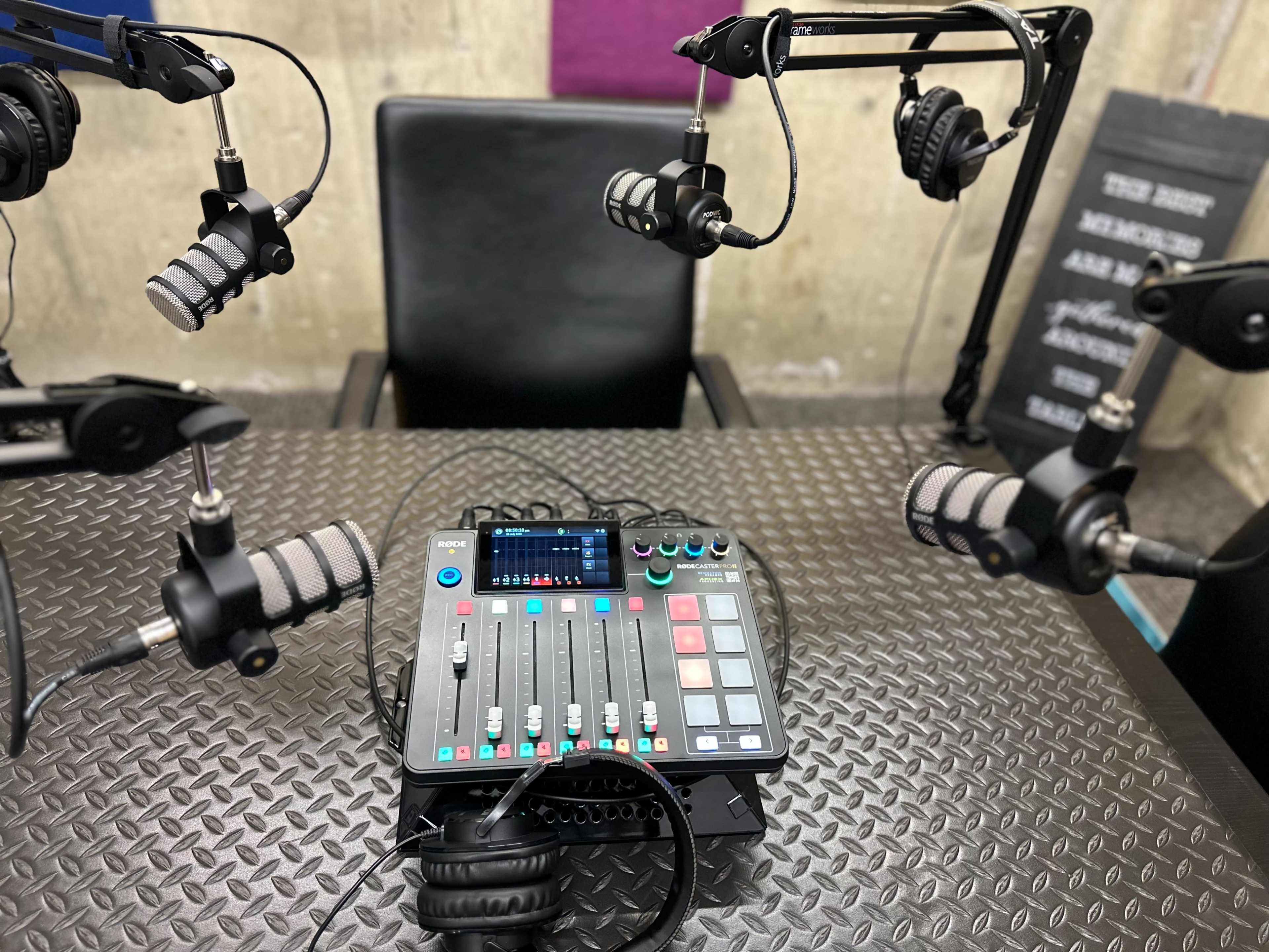 A control panel with microphones is set up in a recording studio next to a chair.