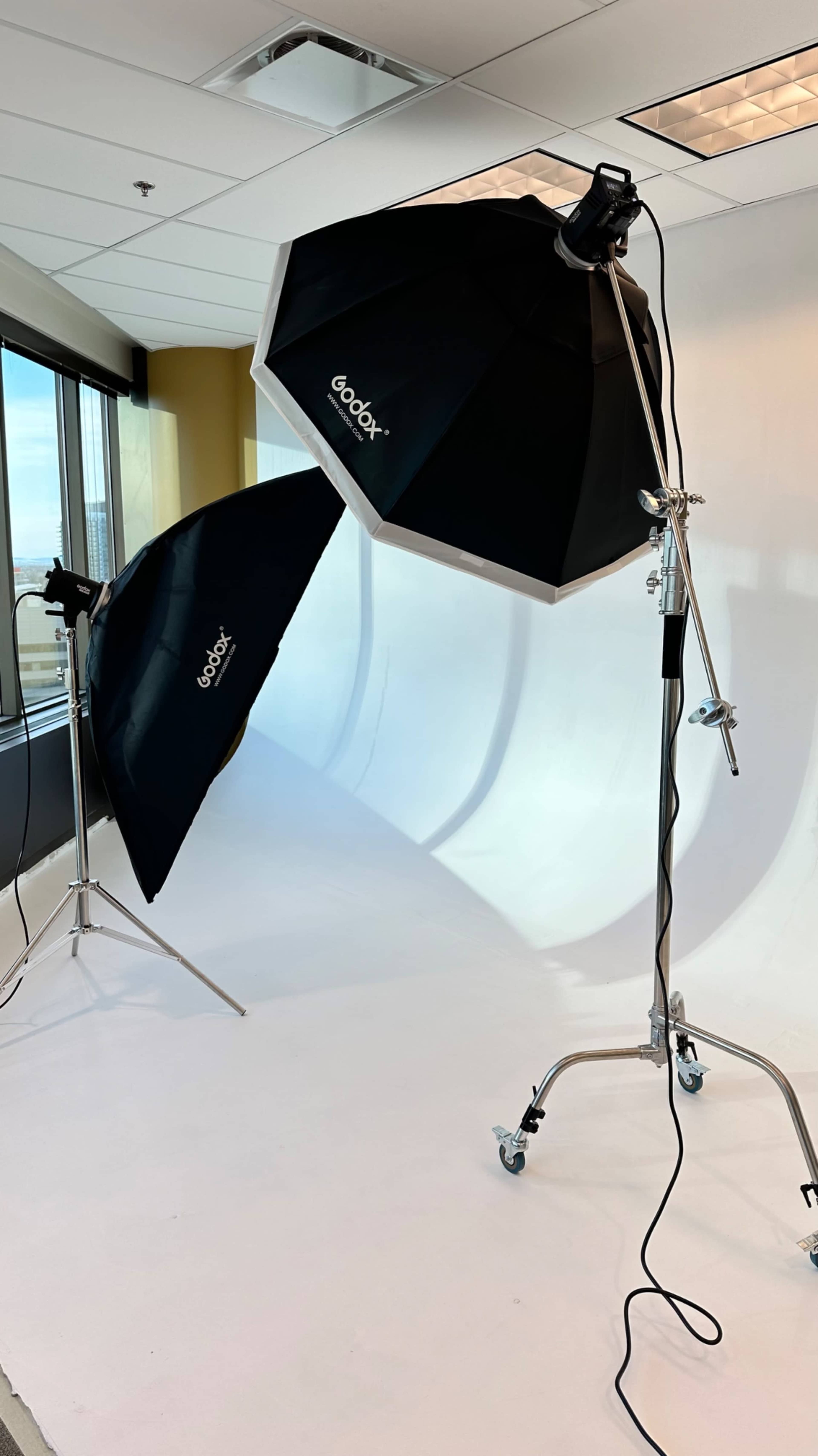 Two softbox lighting setups are positioned next to a white backdrop in a well-lit studio space.