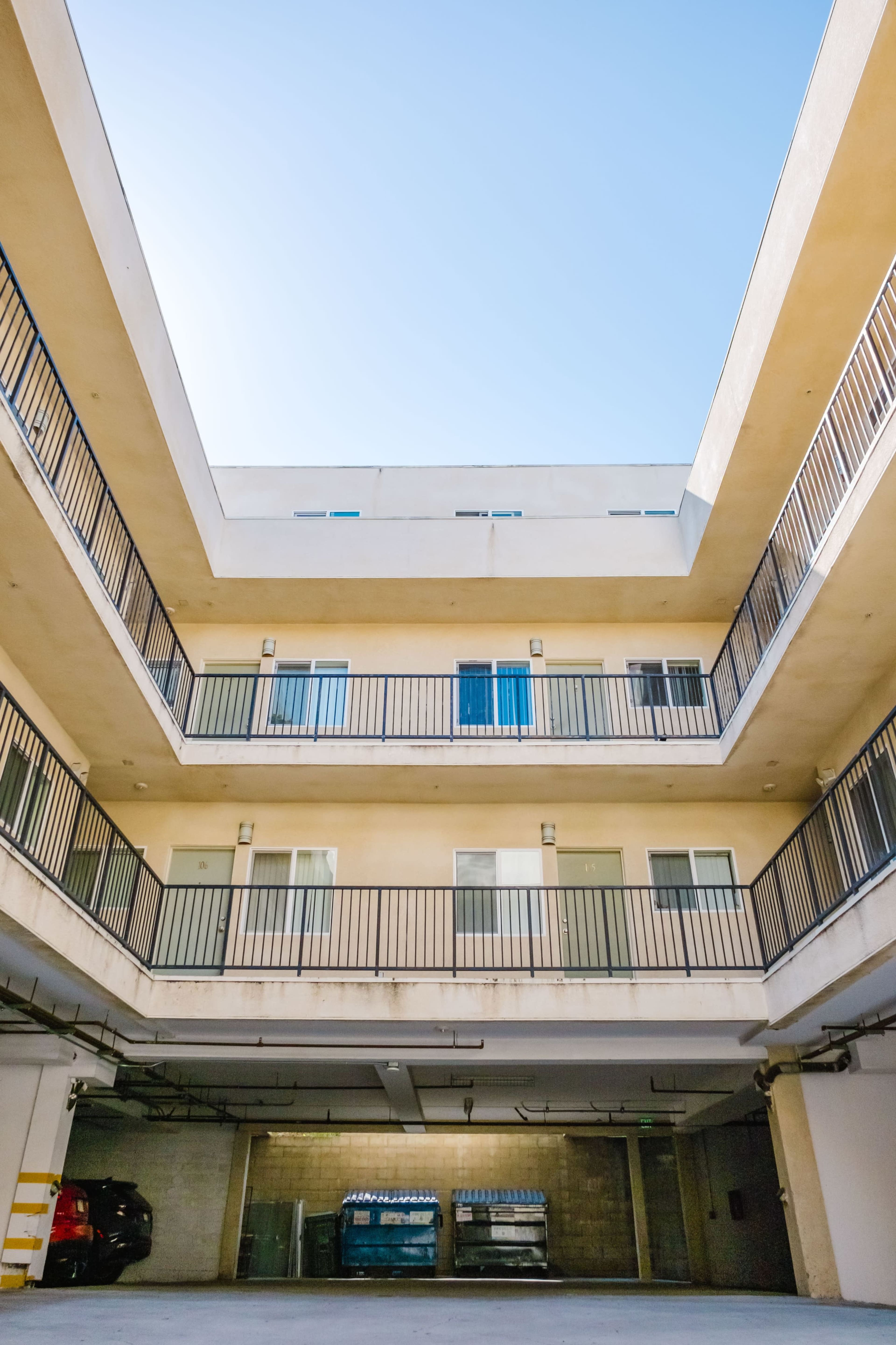 The image shows a multi-story parking structure with a central courtyard and balconies on each level.