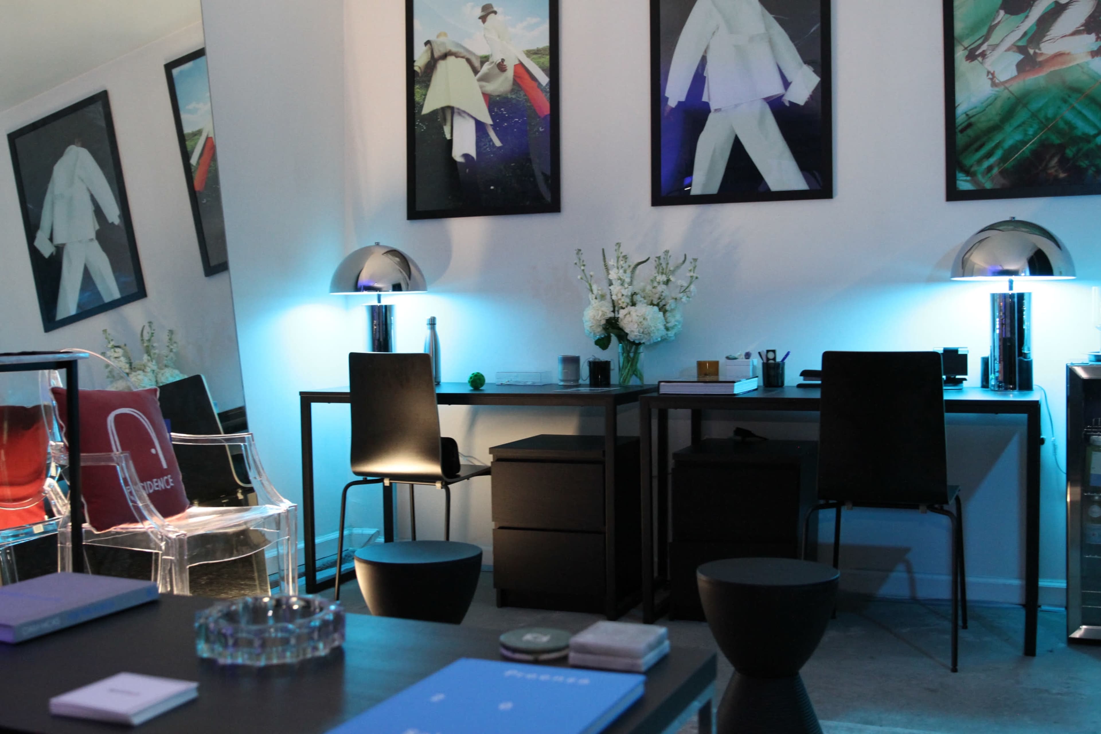 A contemporary office space features sleek furniture, glowing blue lamps, and framed artwork on the walls.