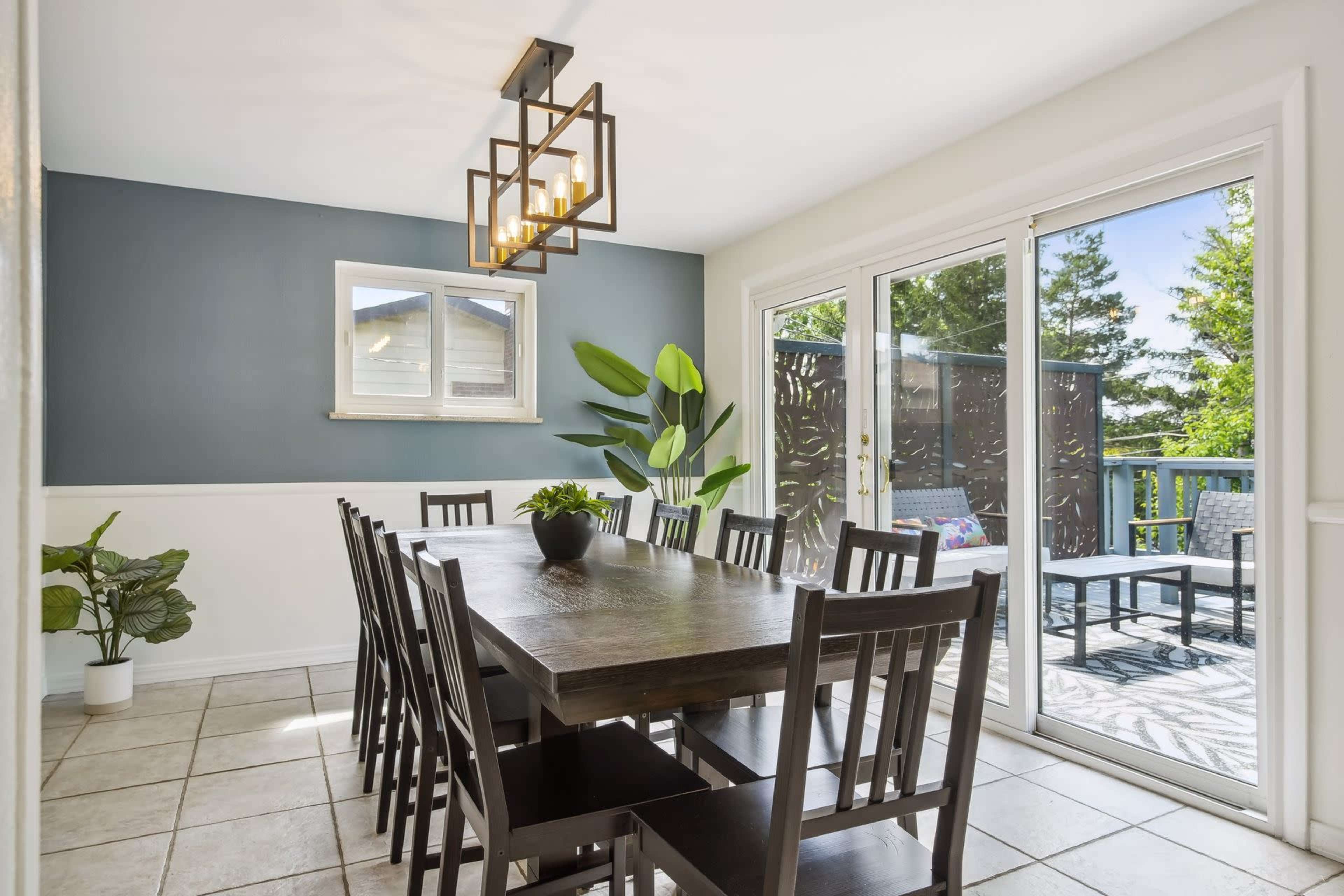 A dining room with a large wooden table surrounded by chairs, and a sliding glass door leading to an outdoor area.