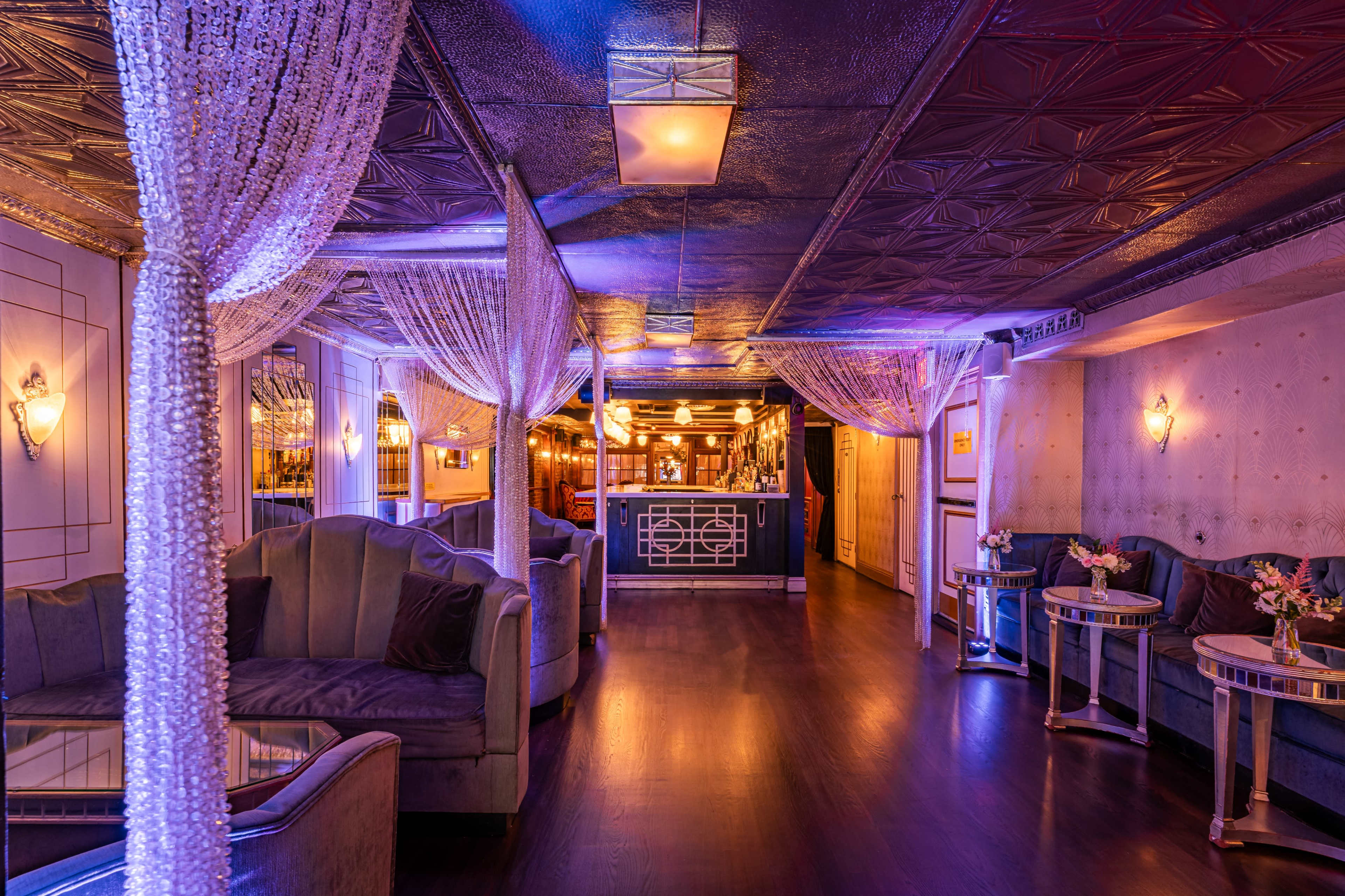 The image shows an elegant lounge interior with plush seating, decorative lighting, and draped fabric accents.