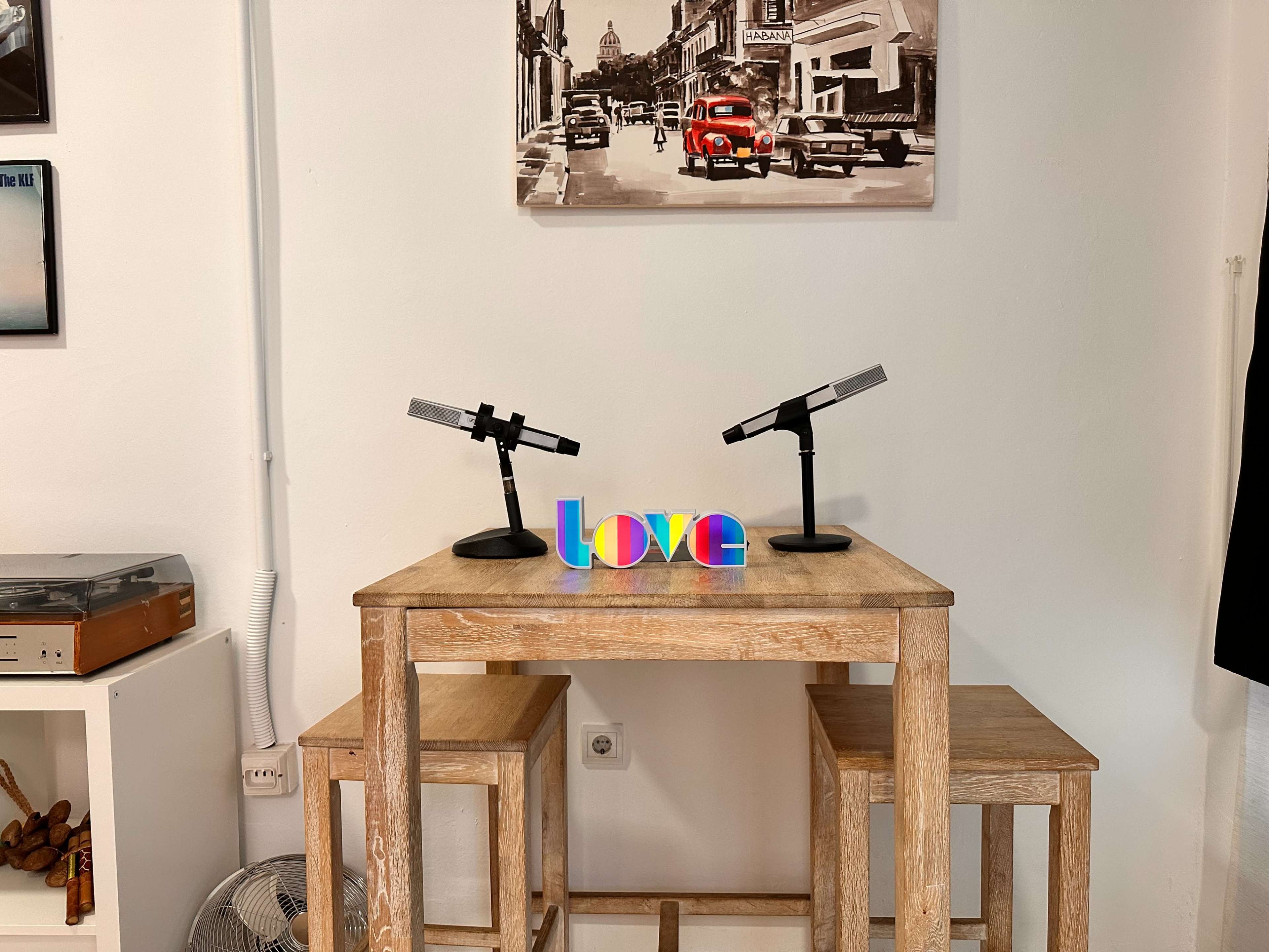 A wooden table with two microphones stands next to colorful letters spelling "love."