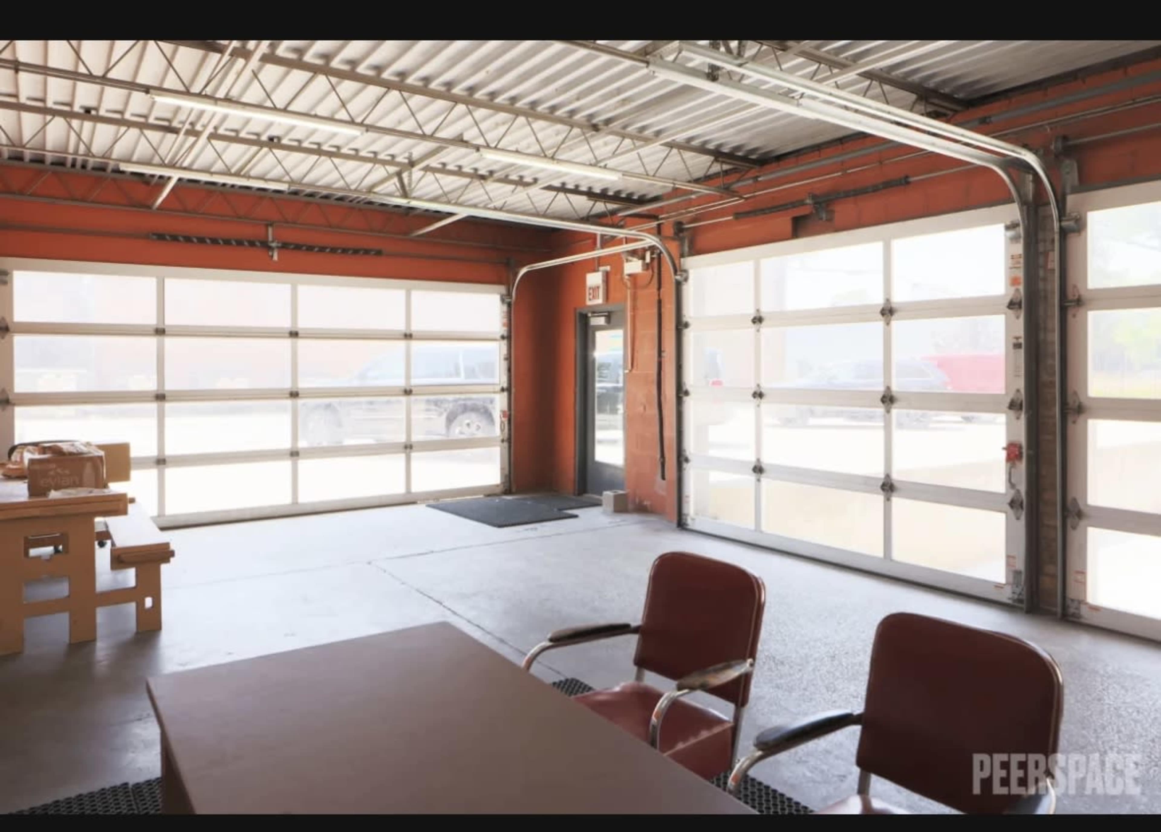 An open garage with large glass doors, a table, and two chairs inside.
