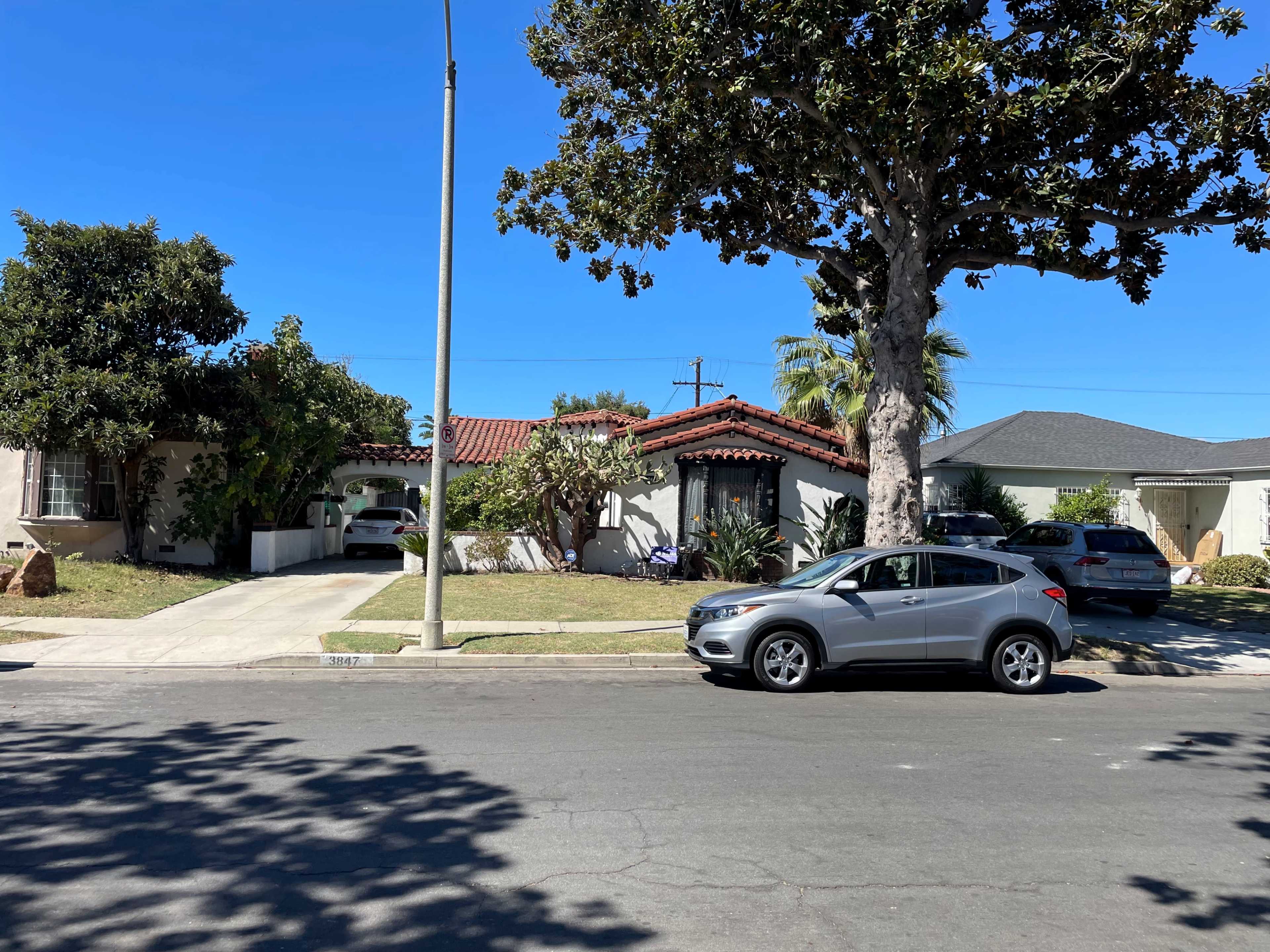 A street view shows two houses with distinct architectural styles, one featuring a red-tiled roof and the other a flat roof, along with parked cars.