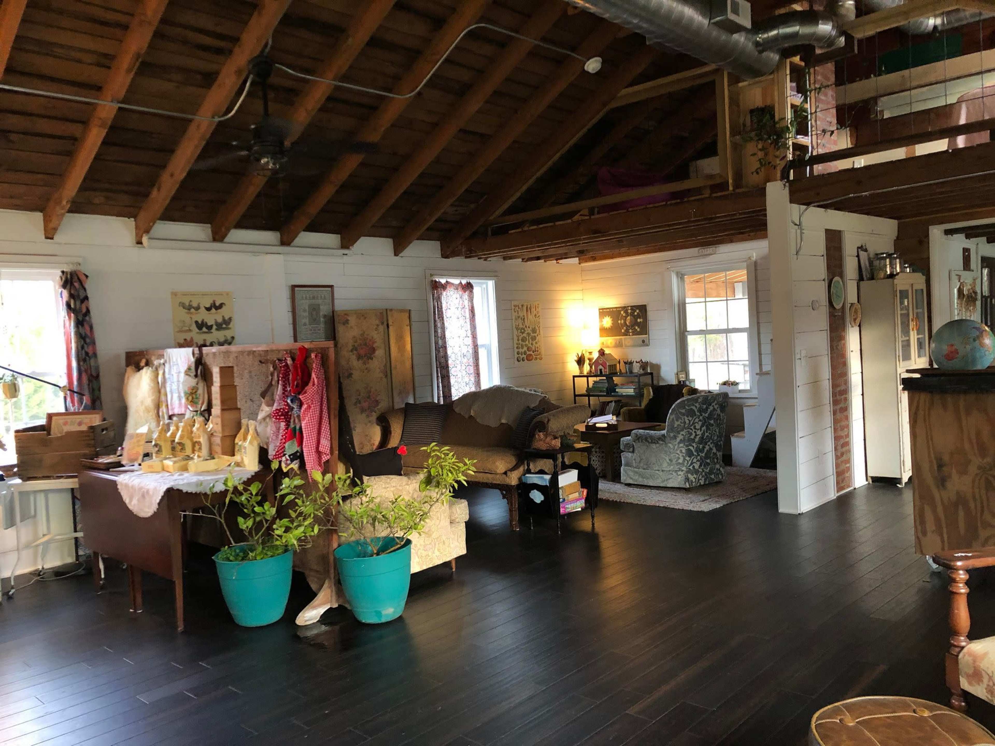 An interior of a spacious, rustic-style living area with a high wooden ceiling, various seating arrangements, and decorative items scattered throughout.