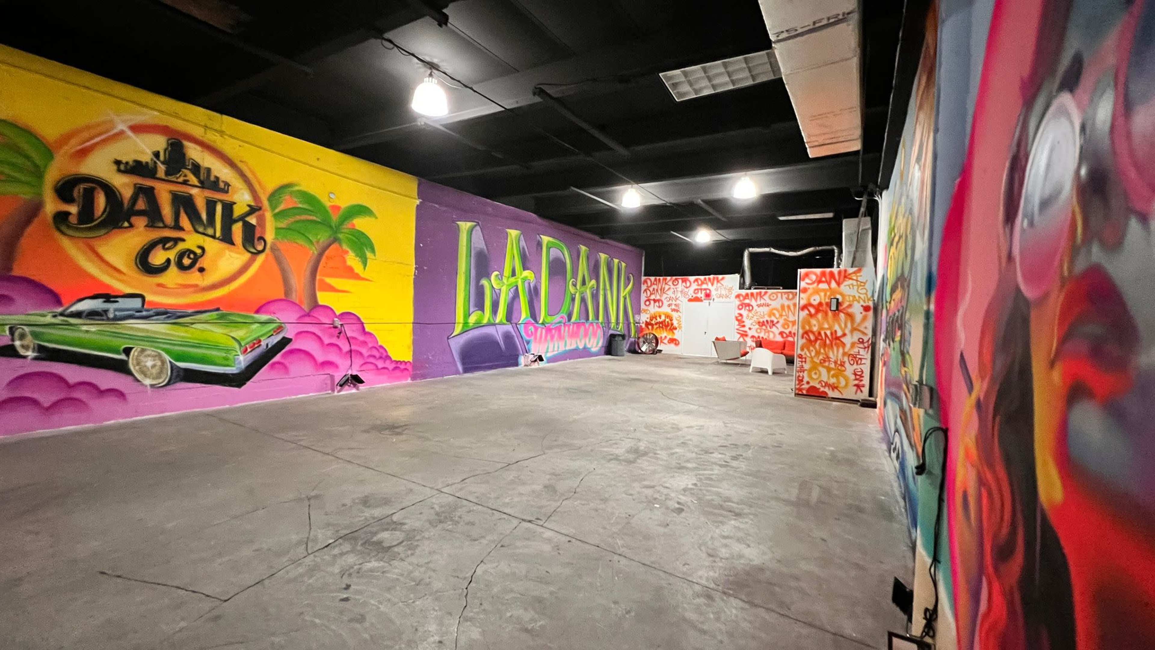 The image shows an indoor space with colorful graffiti murals on the walls, including a vintage car and various artistic designs.