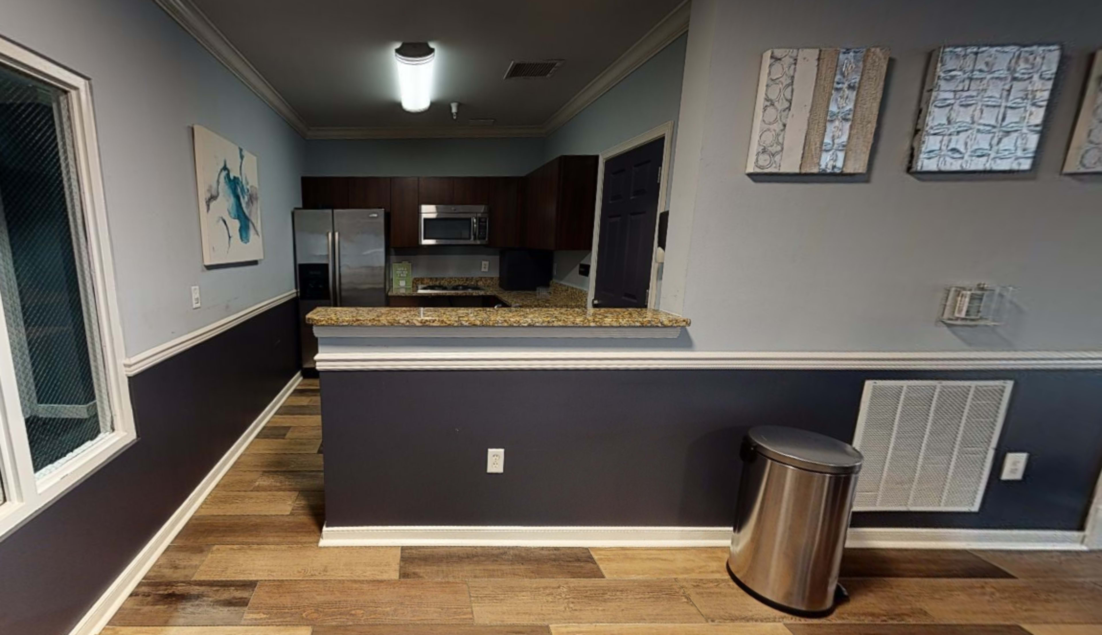 A modern kitchen with granite countertops, stainless steel appliances, and a combination of light blue and dark blue walls.