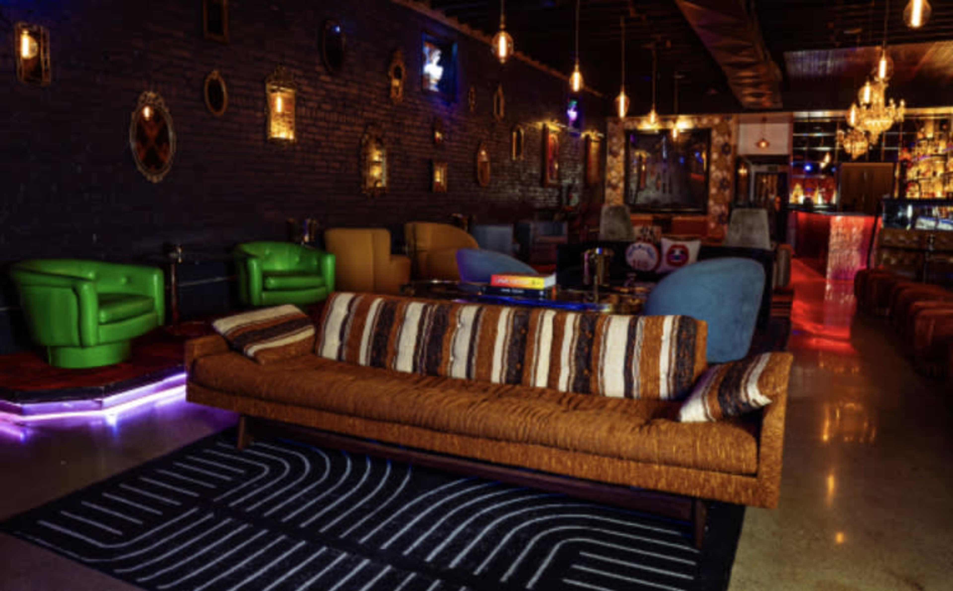 A stylish lounge with colorful seating, a bar area, and decorative lighting.