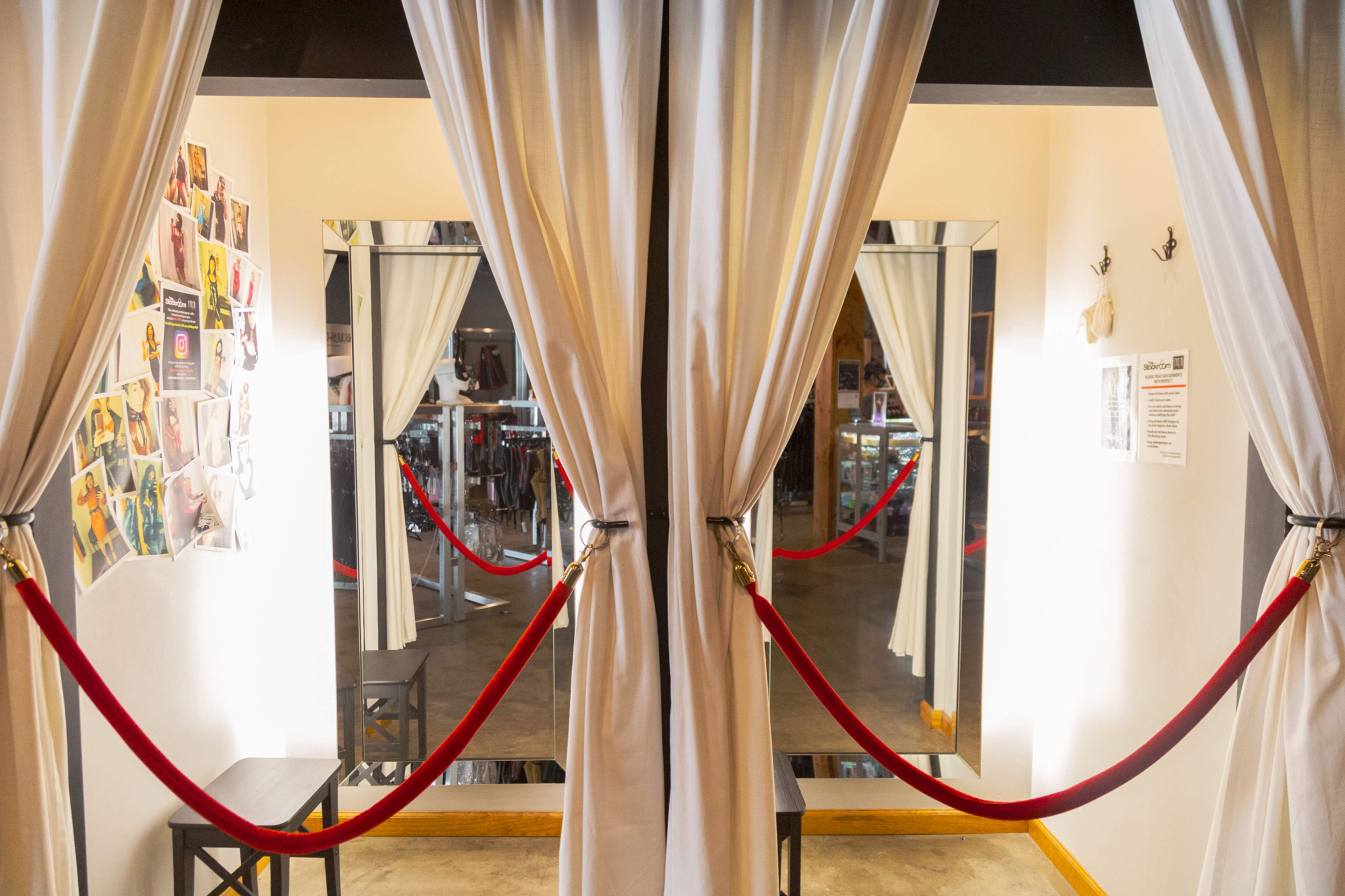 A hallway with two large mirrors flanked by curtains, separated by red ropes.