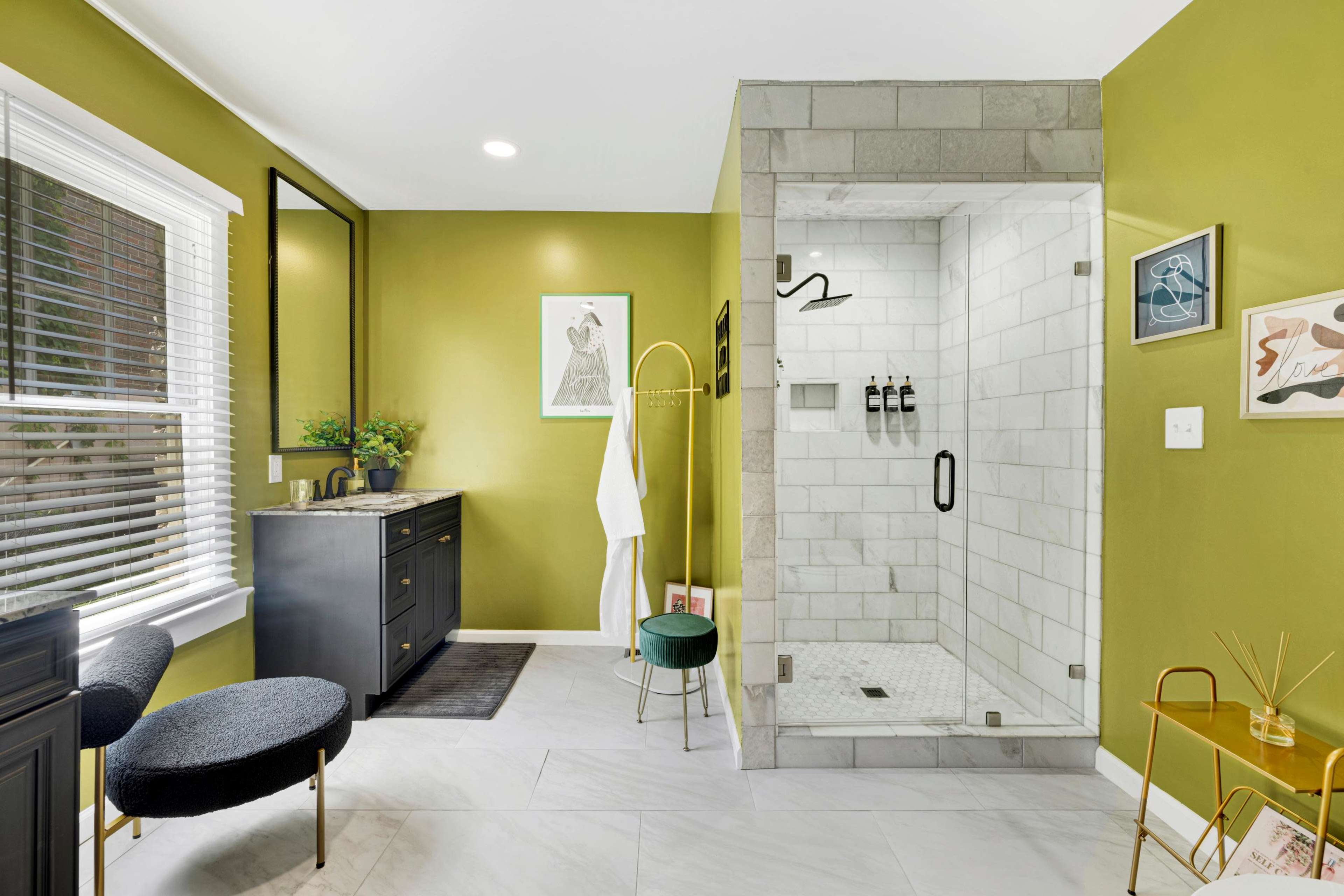 A modern bathroom featuring a walk-in shower with gray tiles, a dark vanity with a mirror, and green walls.