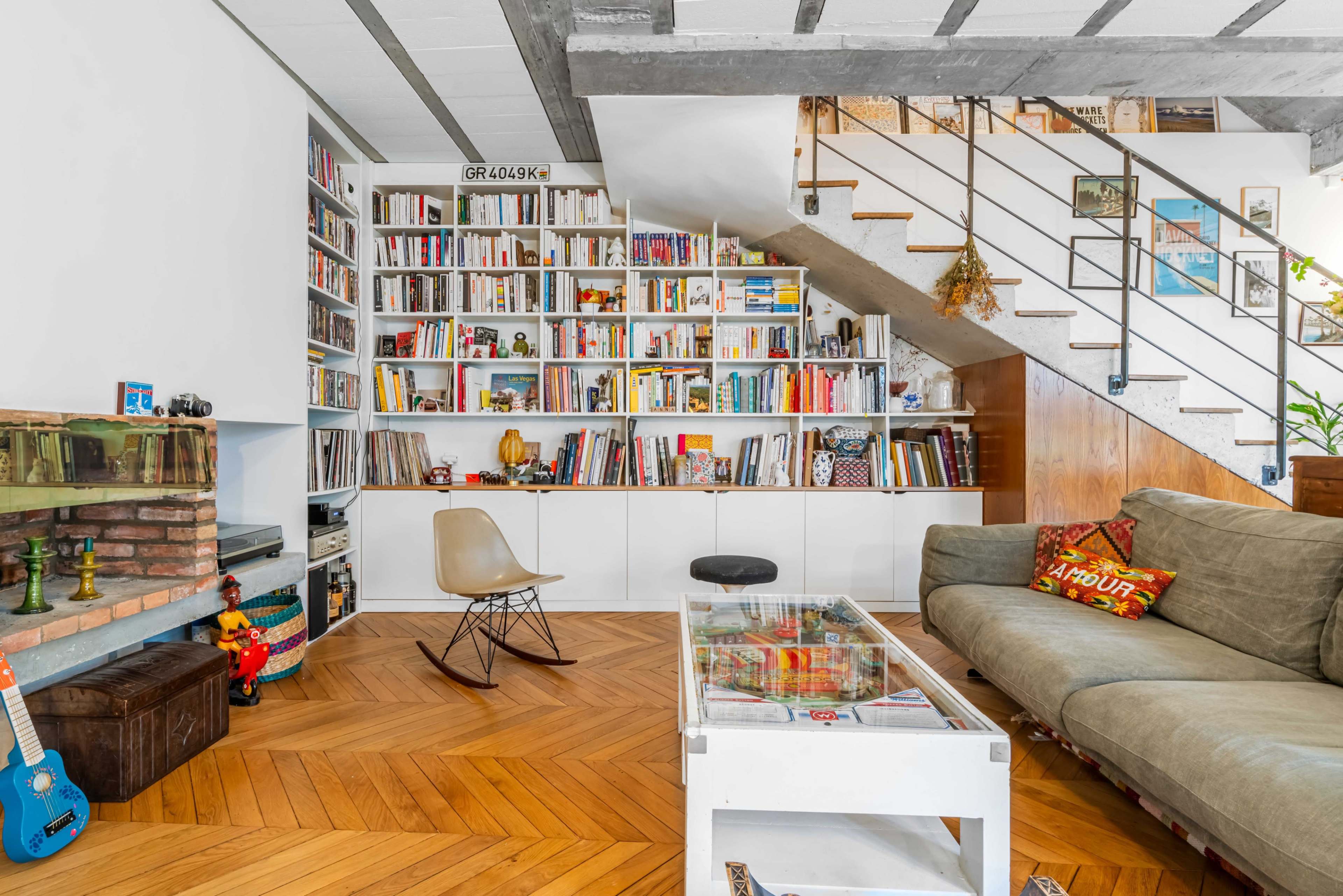 A modern living room features a large bookshelf filled with books, a cozy couch, and a coffee table on a wooden floor.