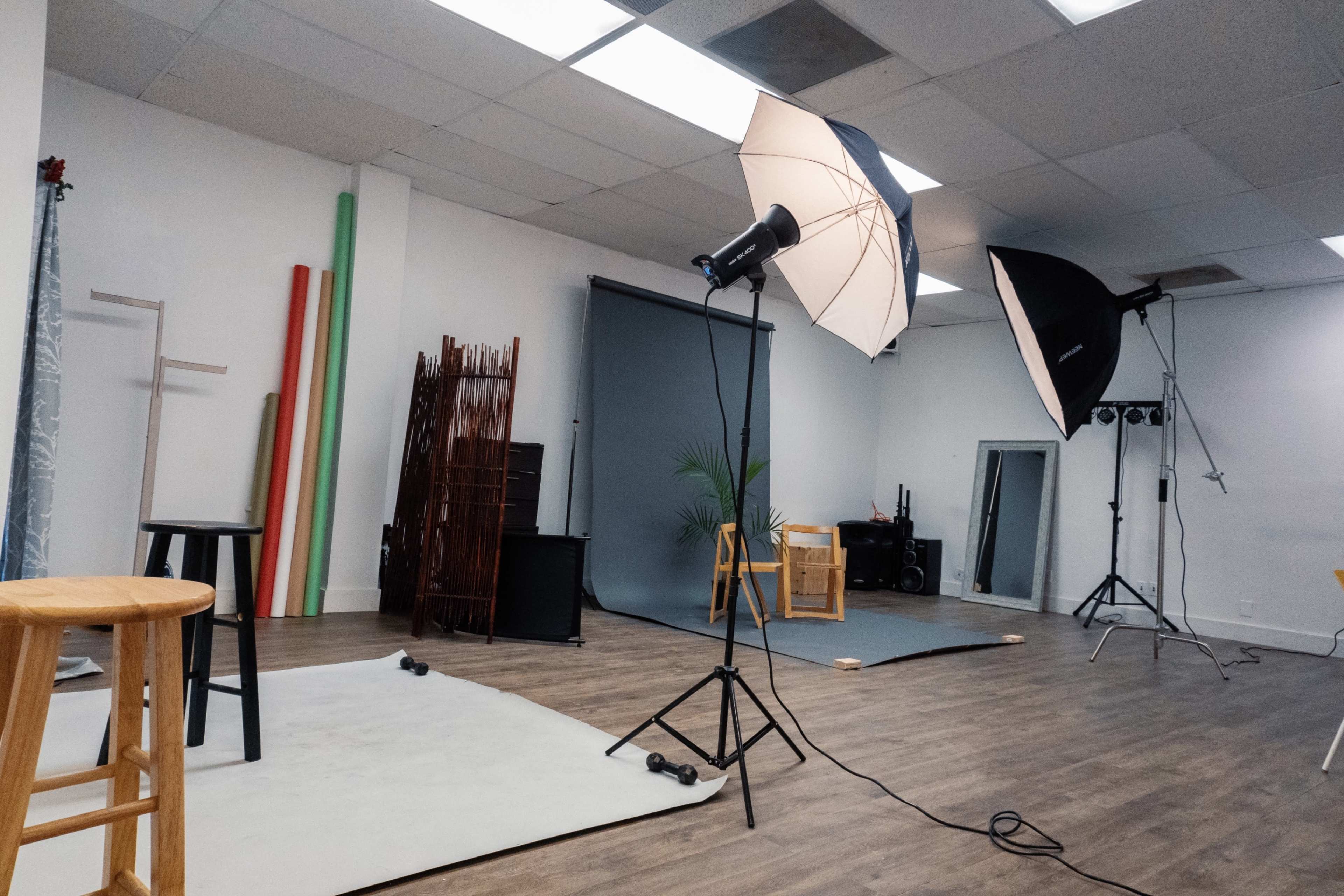 A photography studio with various lighting setups, backdrops, and props arranged on the floor.