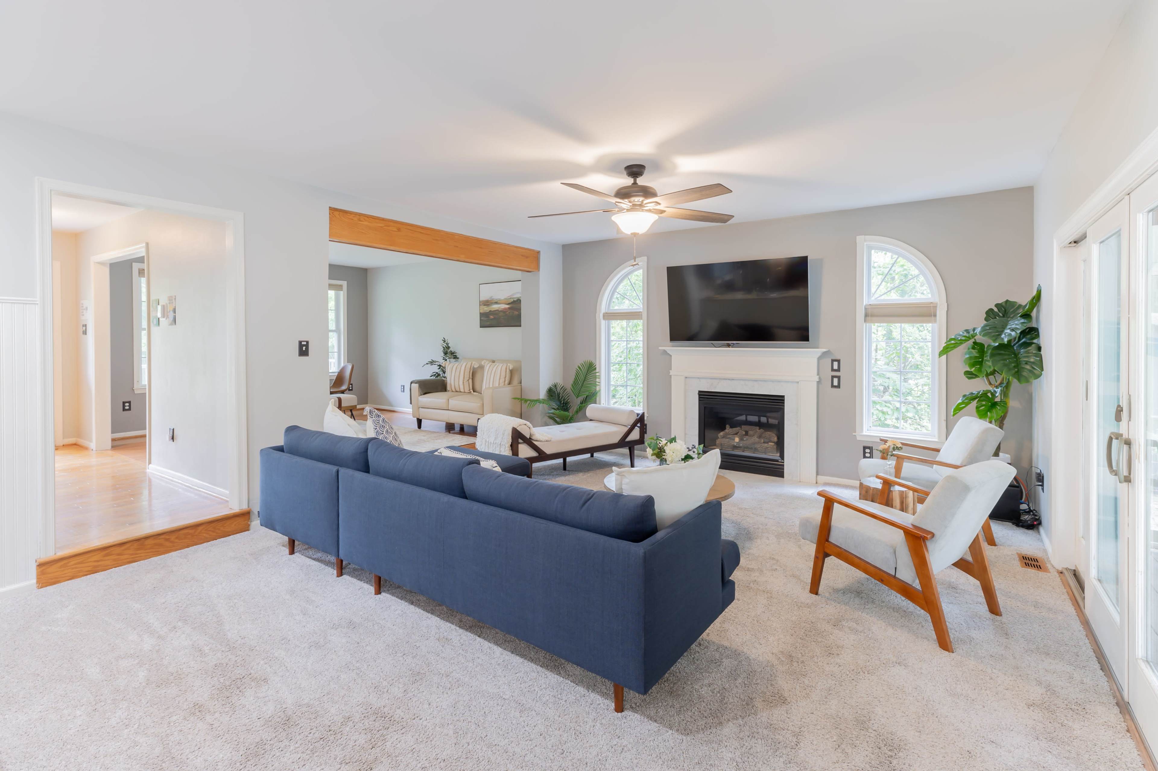 The living room features a blue sectional sofa, a fireplace, and large windows allowing natural light to illuminate the space.