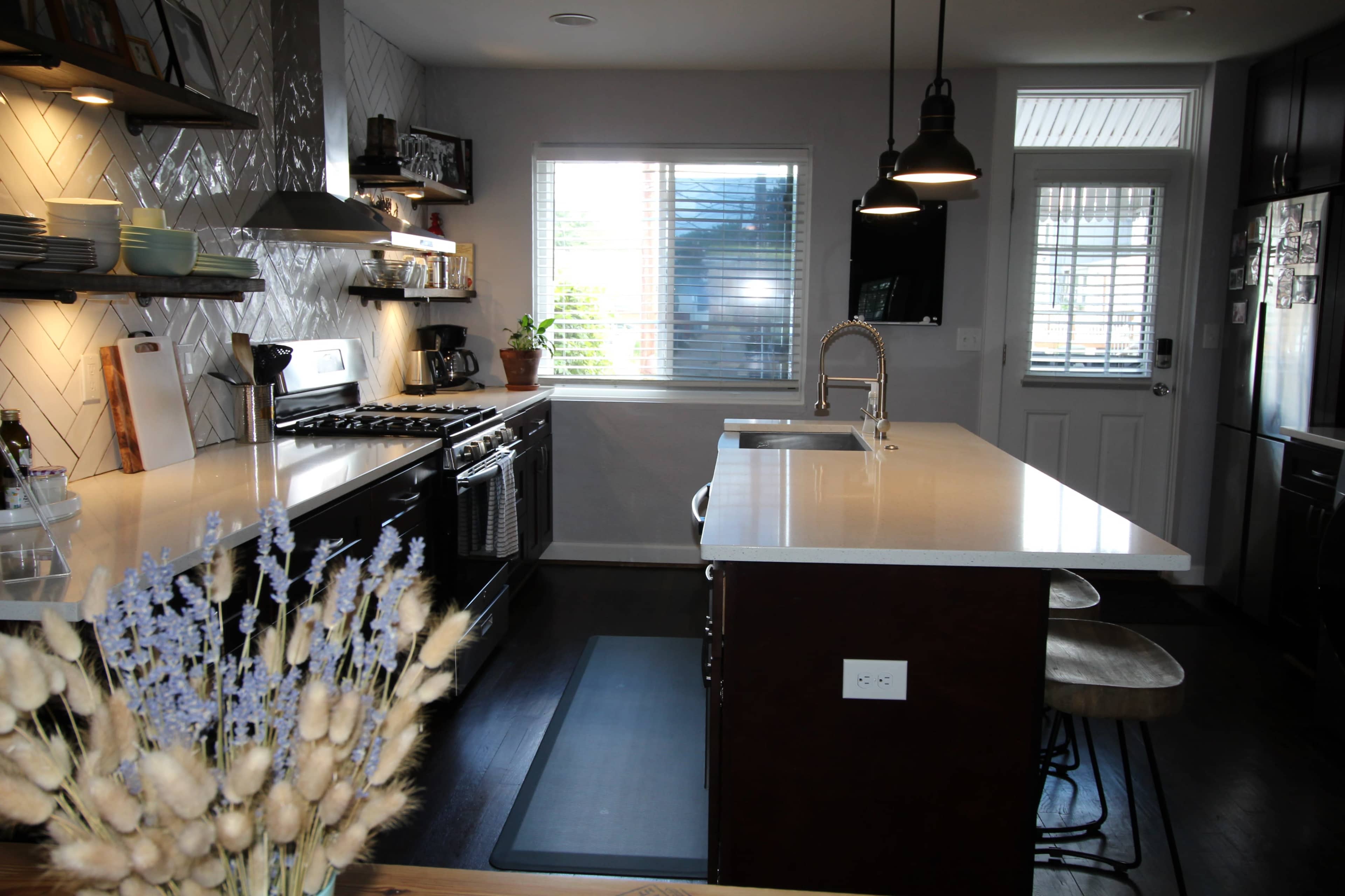 A modern kitchen features a central island, stainless steel appliances, and a bright window with a view.