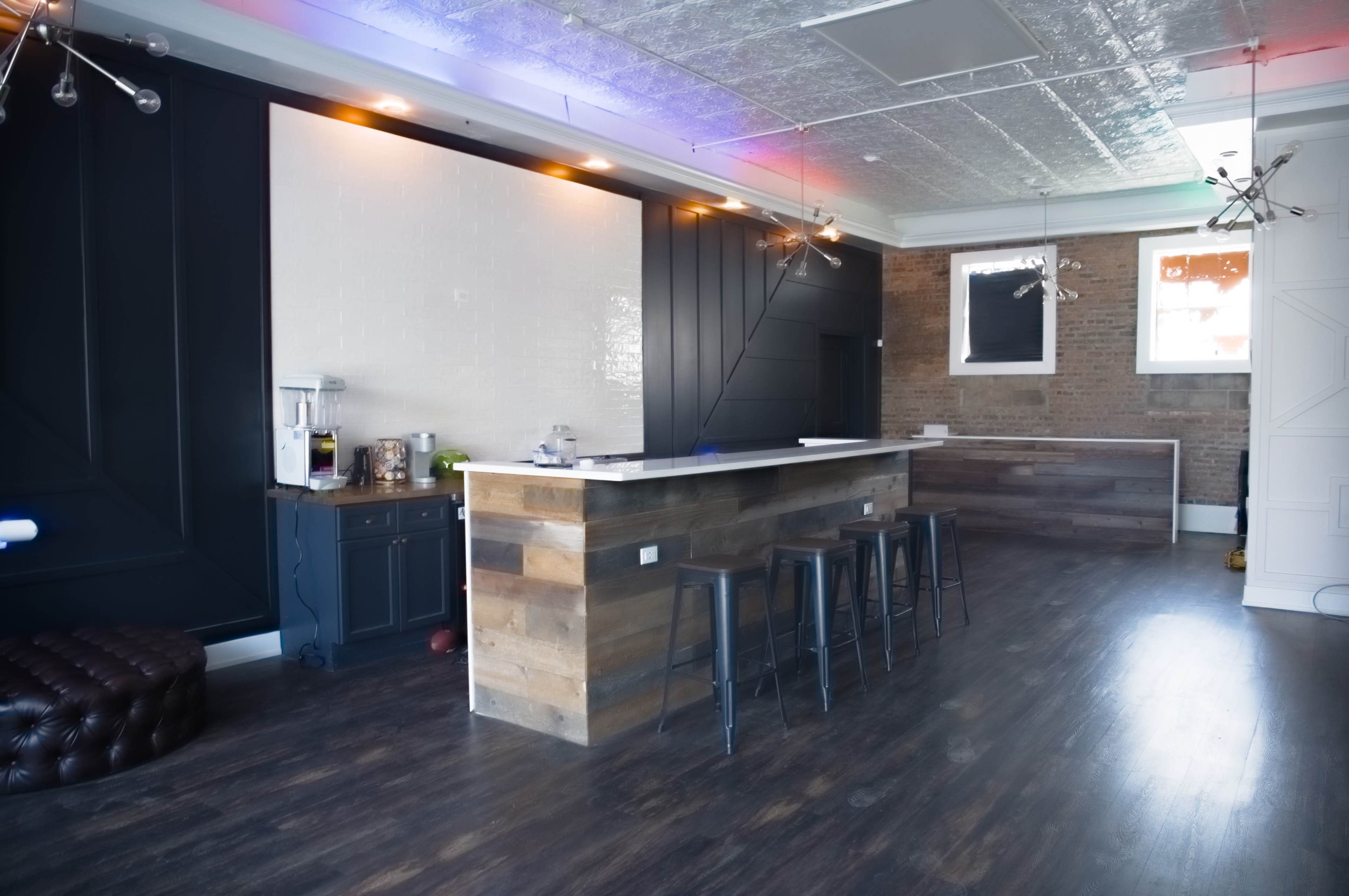 A modern interior of a cafe or bar with a wooden counter, dark walls, and stylish lighting fixtures.