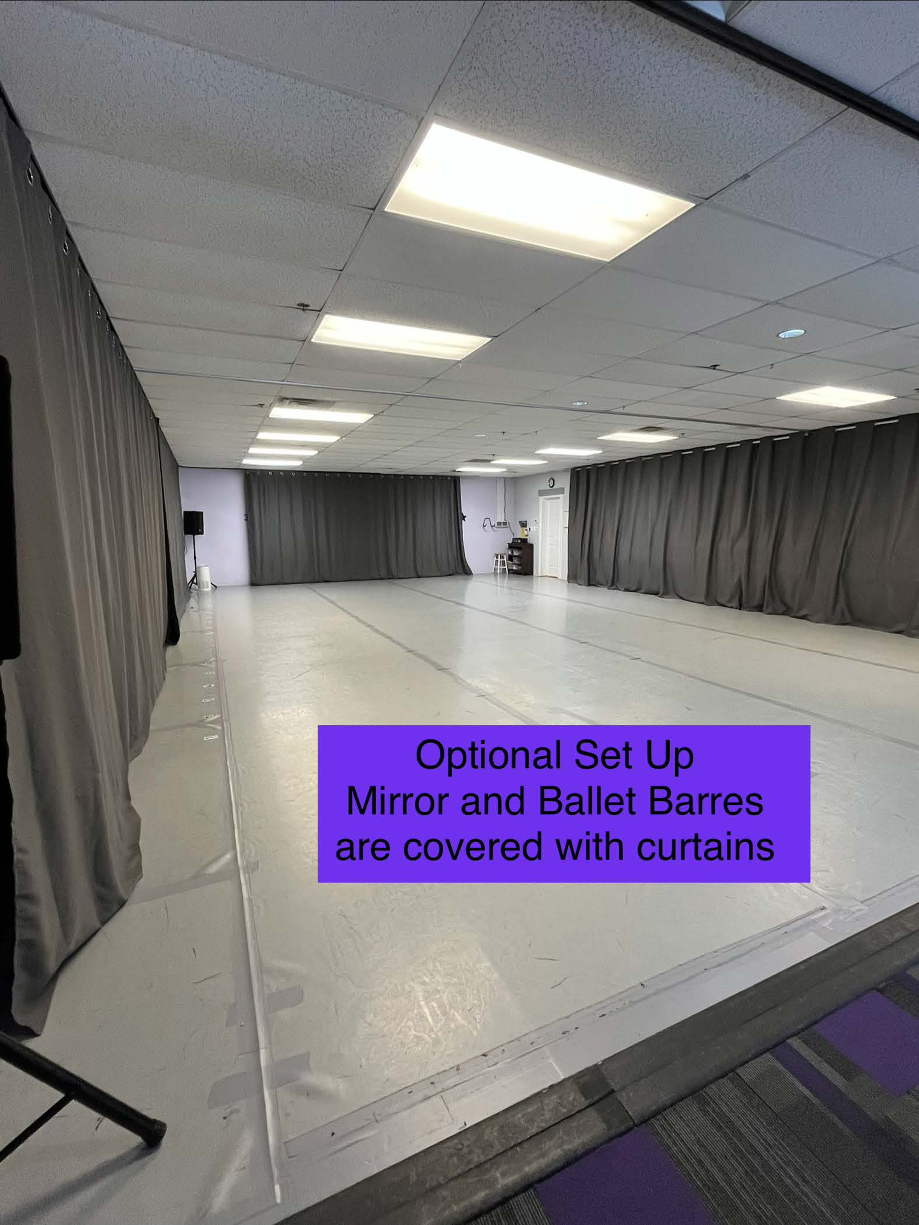 The image shows an empty dance studio with a mirrored wall covered by curtains and ballet barres also obscured.