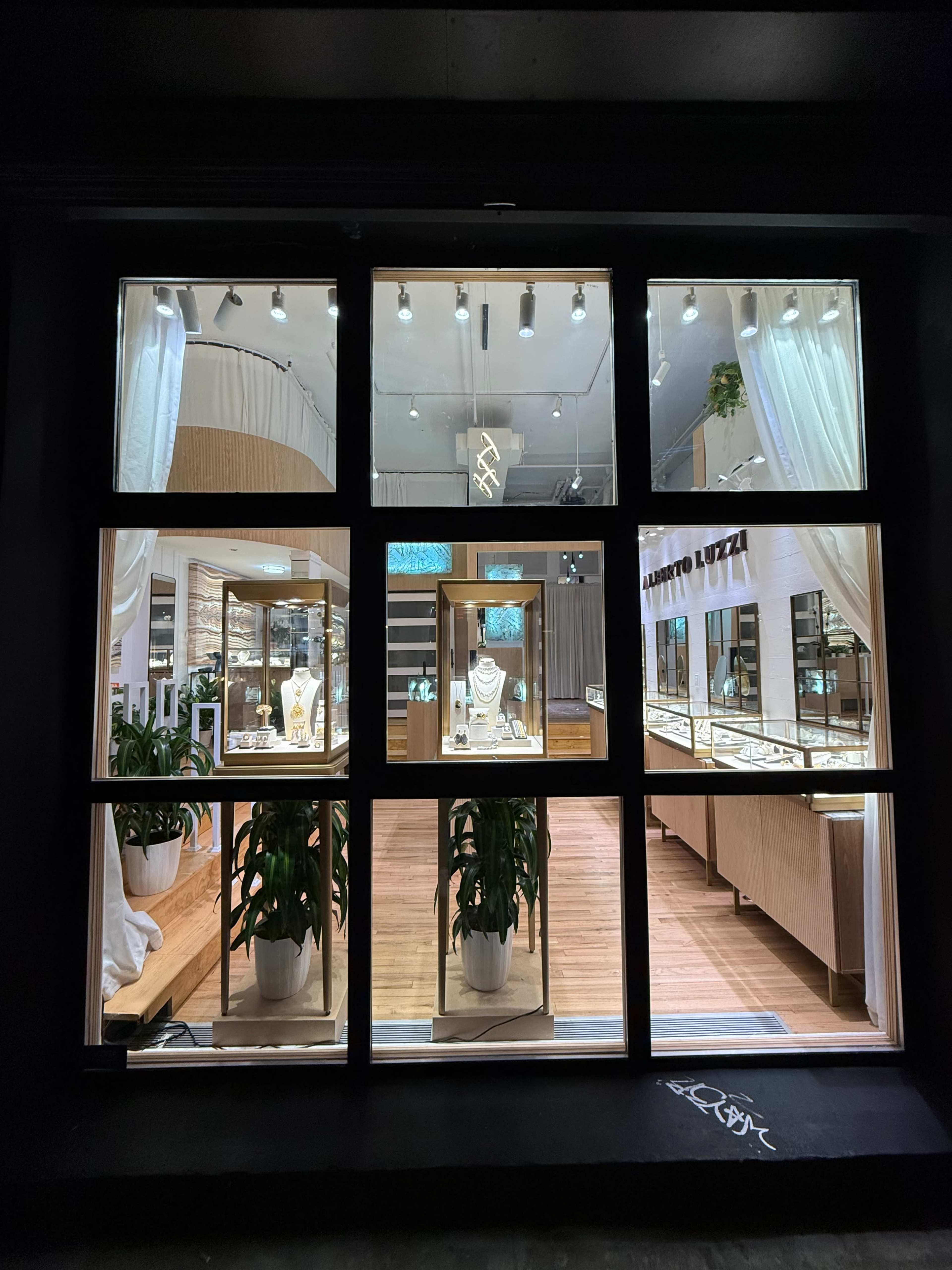 The image shows a jewelry store with display cases filled with various pieces, viewed through large windows framed by a black exterior.