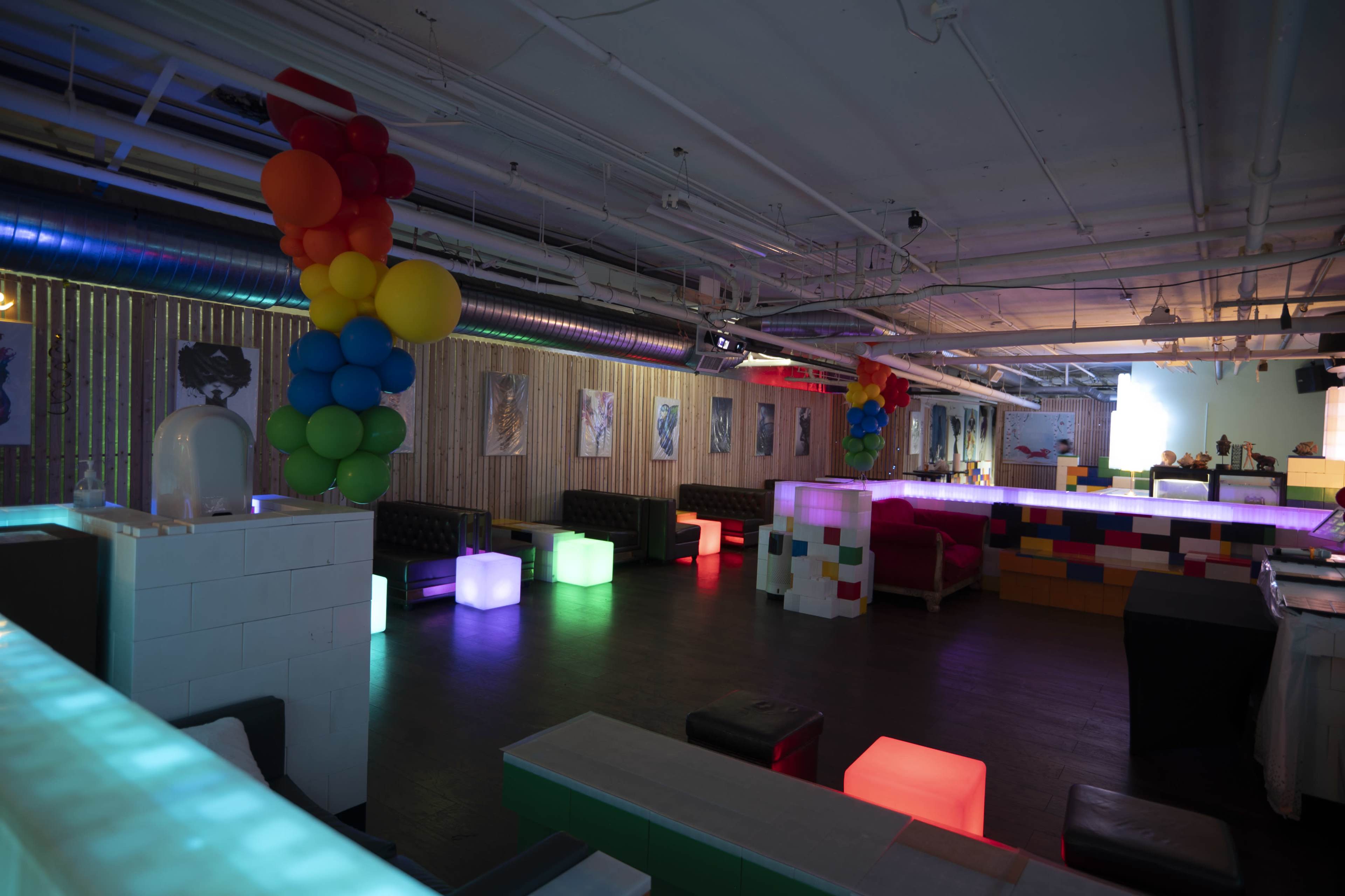 A brightly lit event space with colorful seating and decorative balloons.