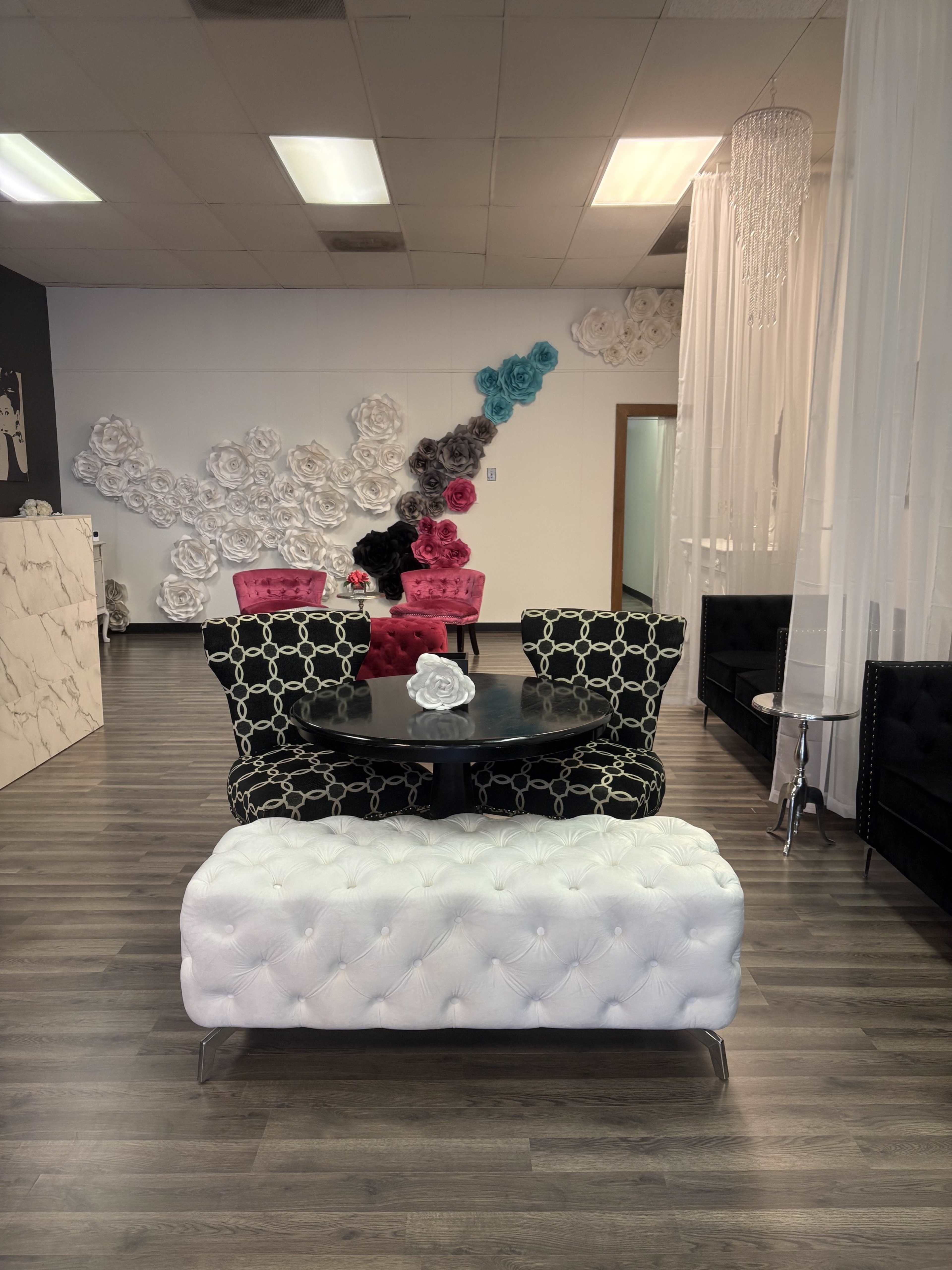 The image shows a modern interior with black and white furniture, including patterned chairs and a tufted white bench, set against a backdrop of decorative wall flowers in various colors.