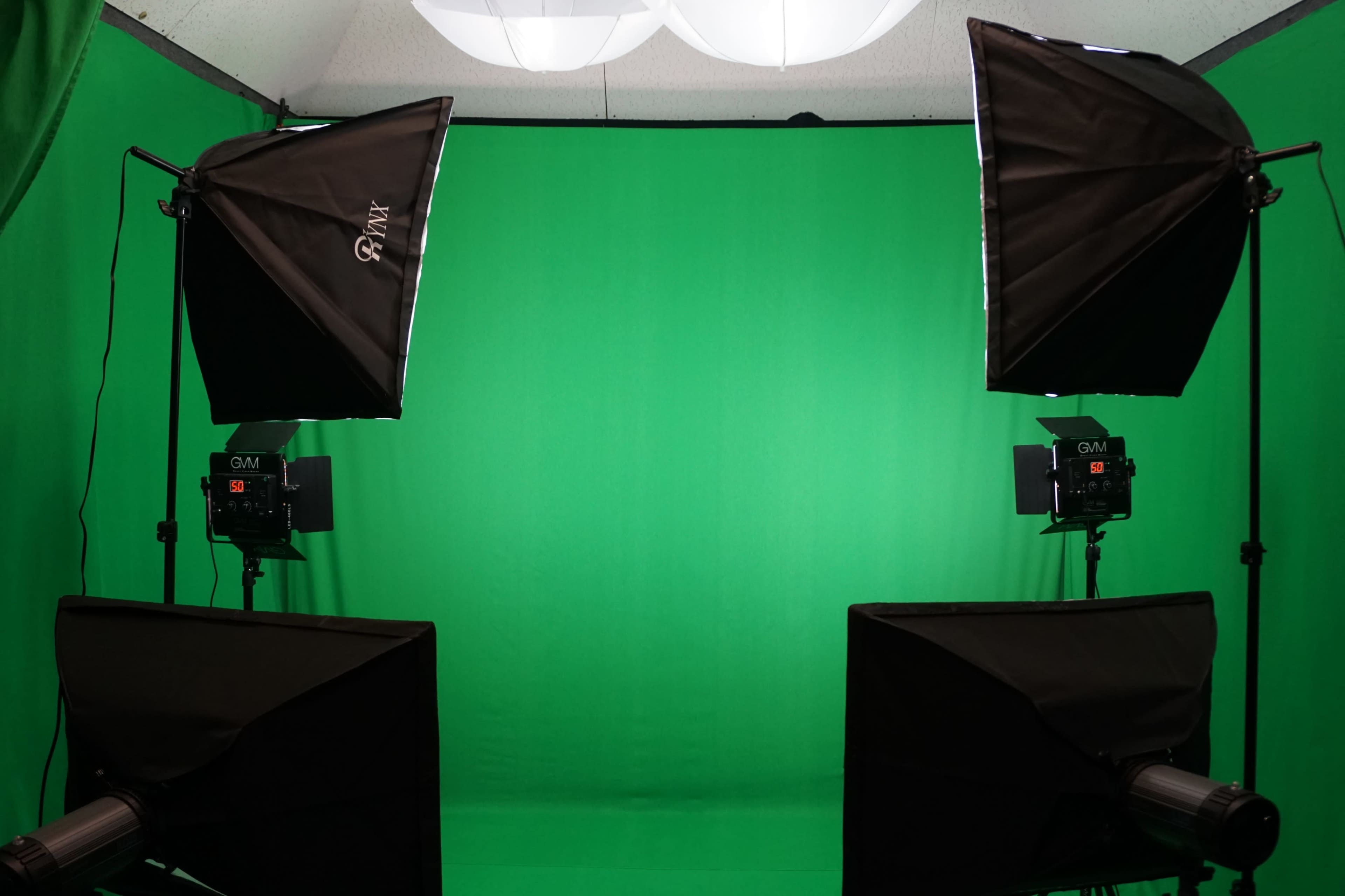 A green screen setup with studio lights on either side, providing an even backdrop for filming or photography.