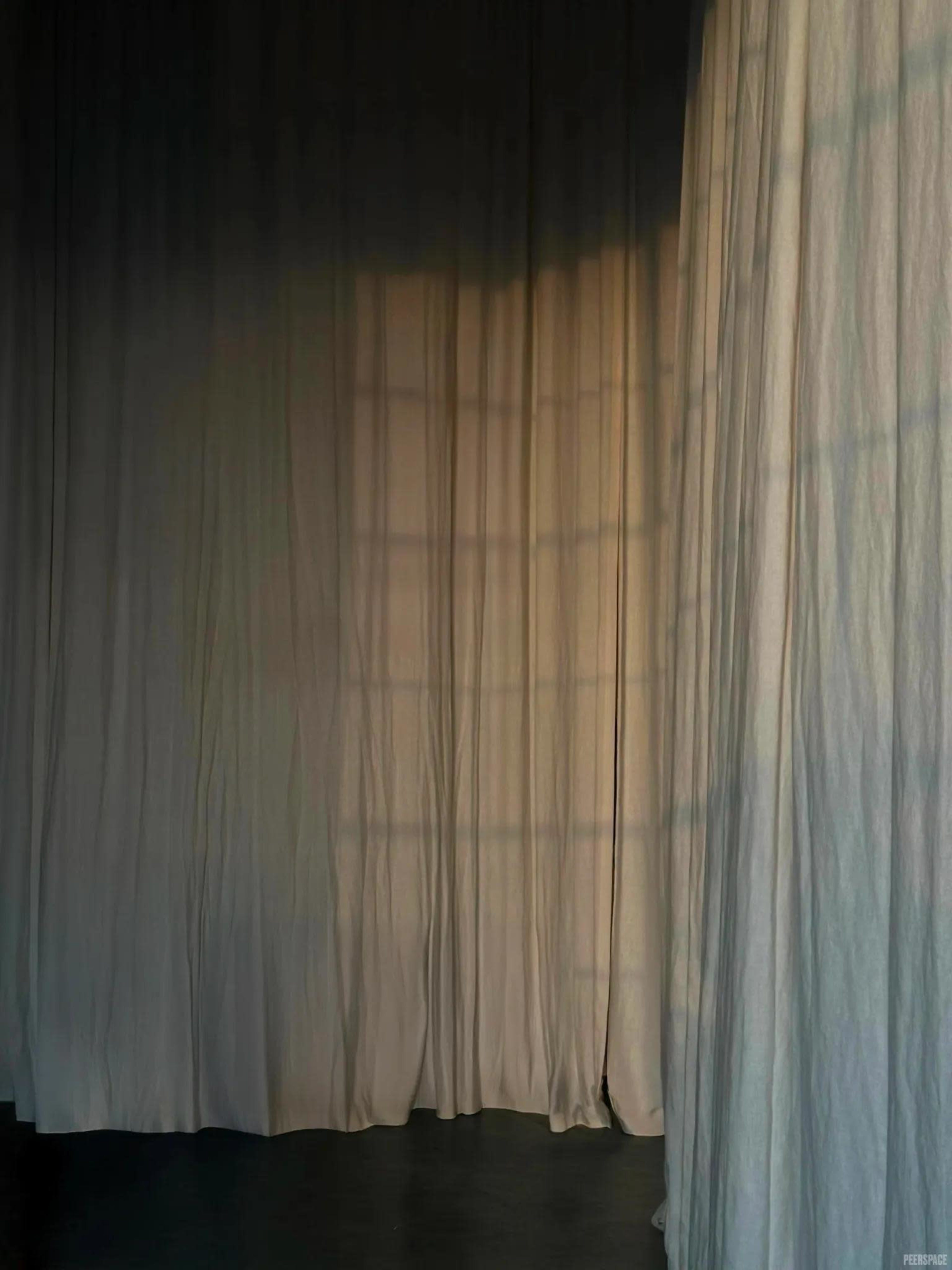 The image shows a softly lit interior space with sheer white curtains casting shadows on the floor.
