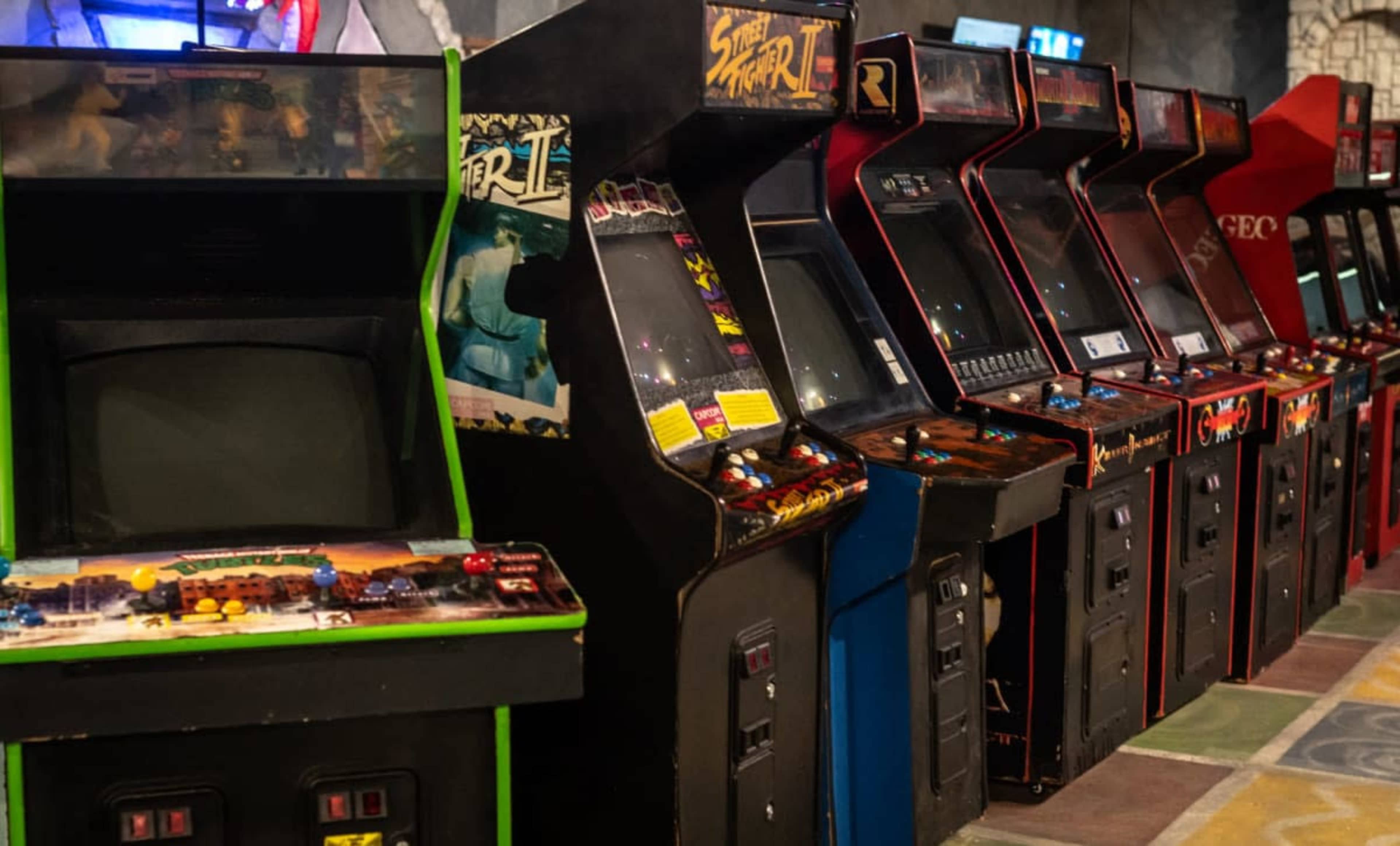 A row of classic arcade game machines is displayed, featuring various titles and colorful designs.