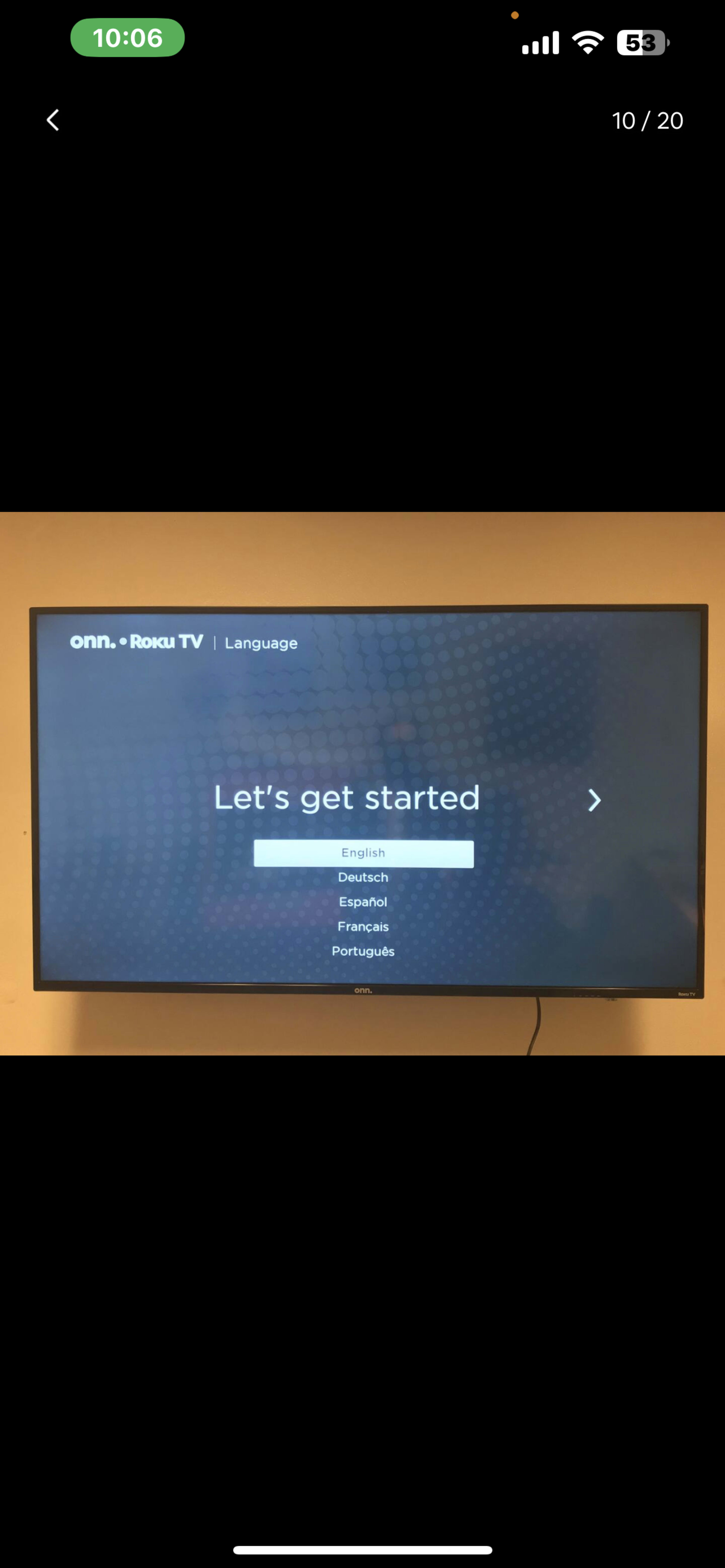 A television screen displays the setup menu for a Roku TV with language options.