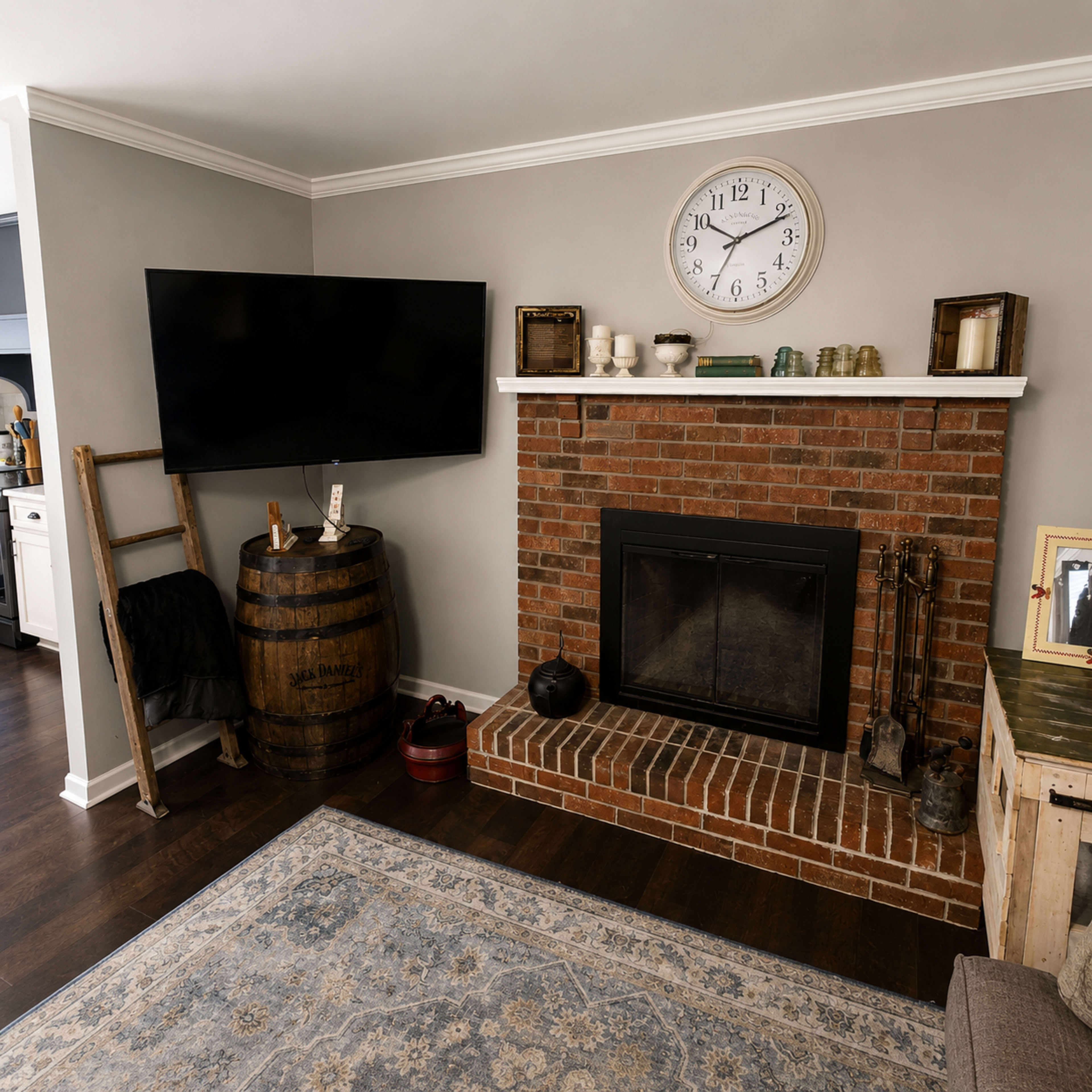 The image shows a living room corner featuring a brick fireplace, a mounted flat-screen TV, a wooden ladder, and a rustic barrel.