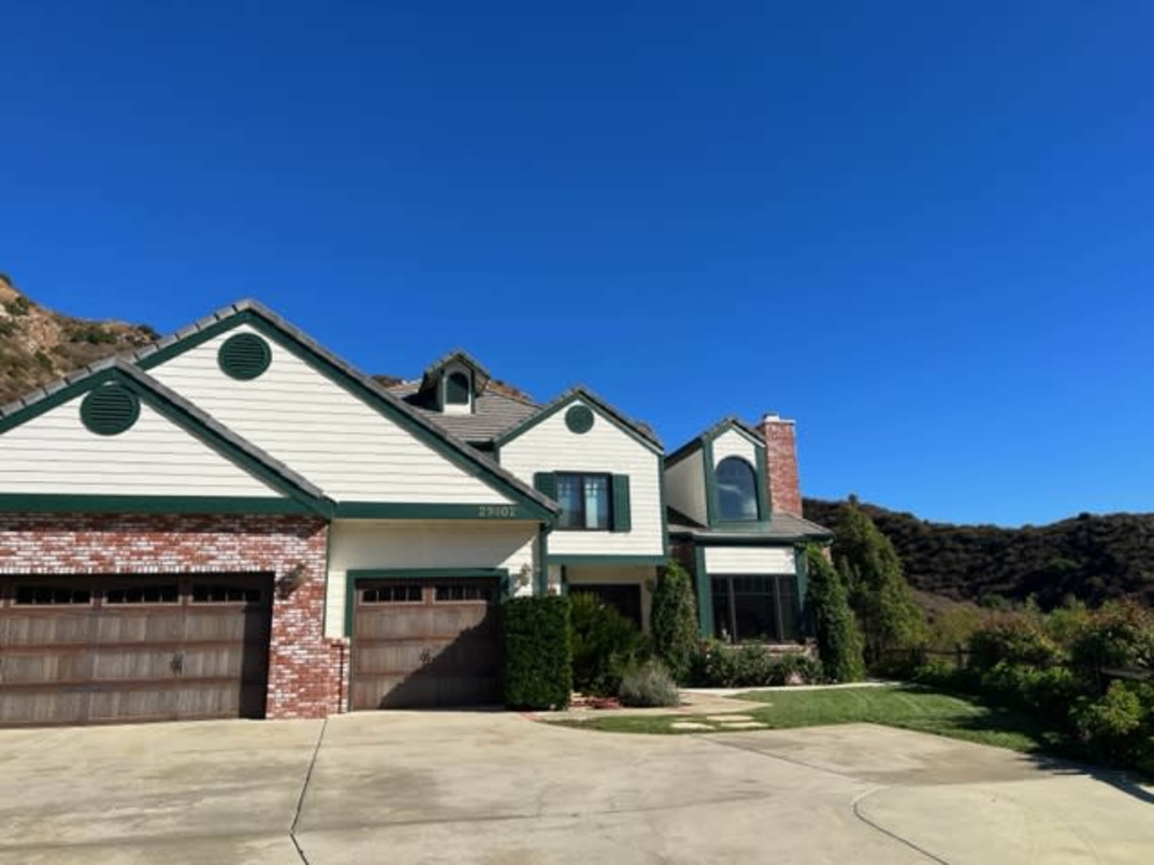 A two-story house with a combination of brick and siding features a well-maintained front yard and a driveway leading to a two-car garage.