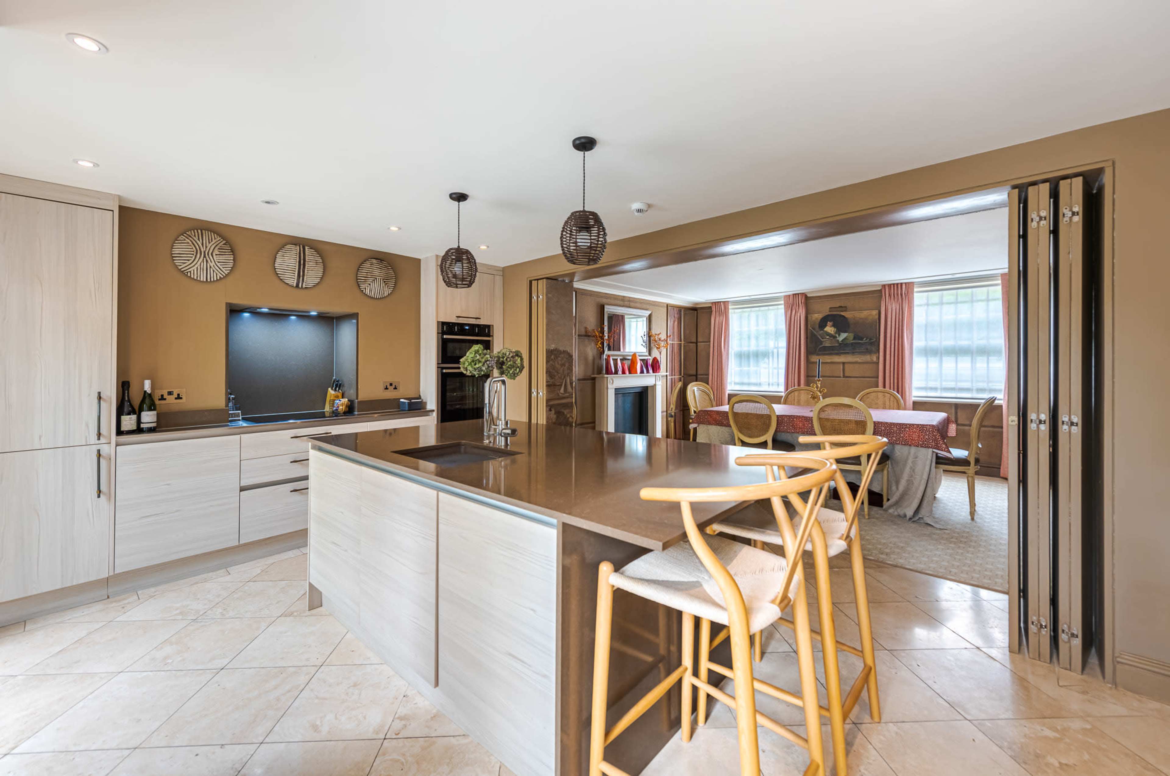 The image shows a modern kitchen with a central island, light-colored cabinets, and a dining area visible in the background.