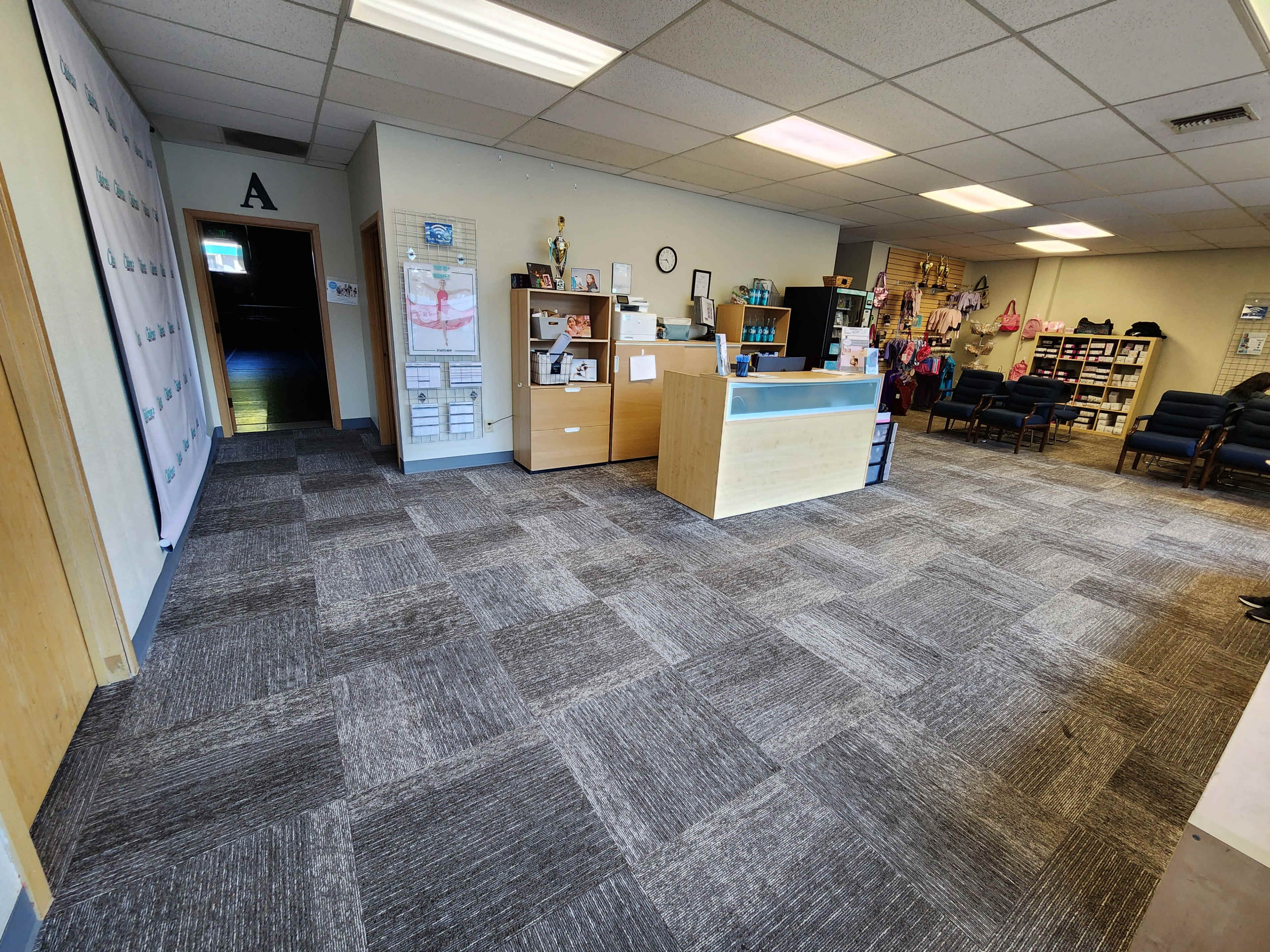 A spacious office reception area with a front desk, shelving units, and seating areas.