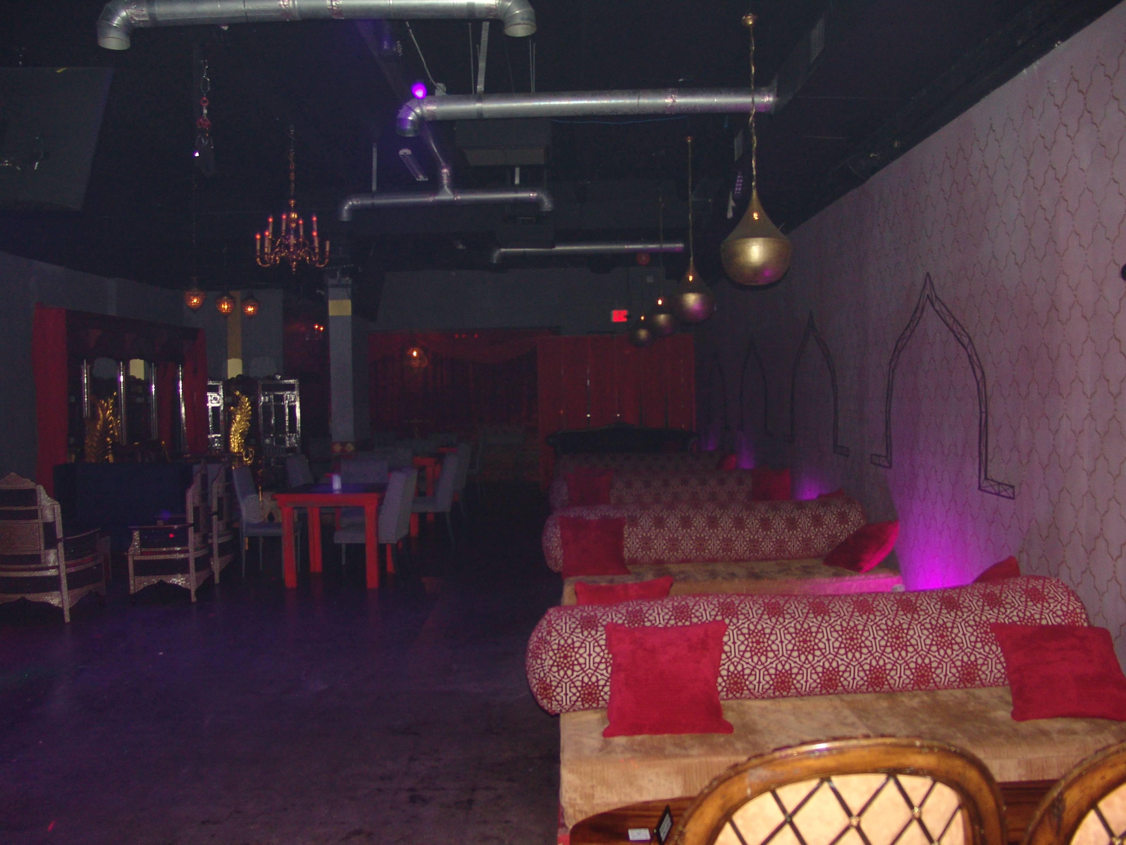 An empty lounge with low seating, dim lighting, and decorative wall patterns.