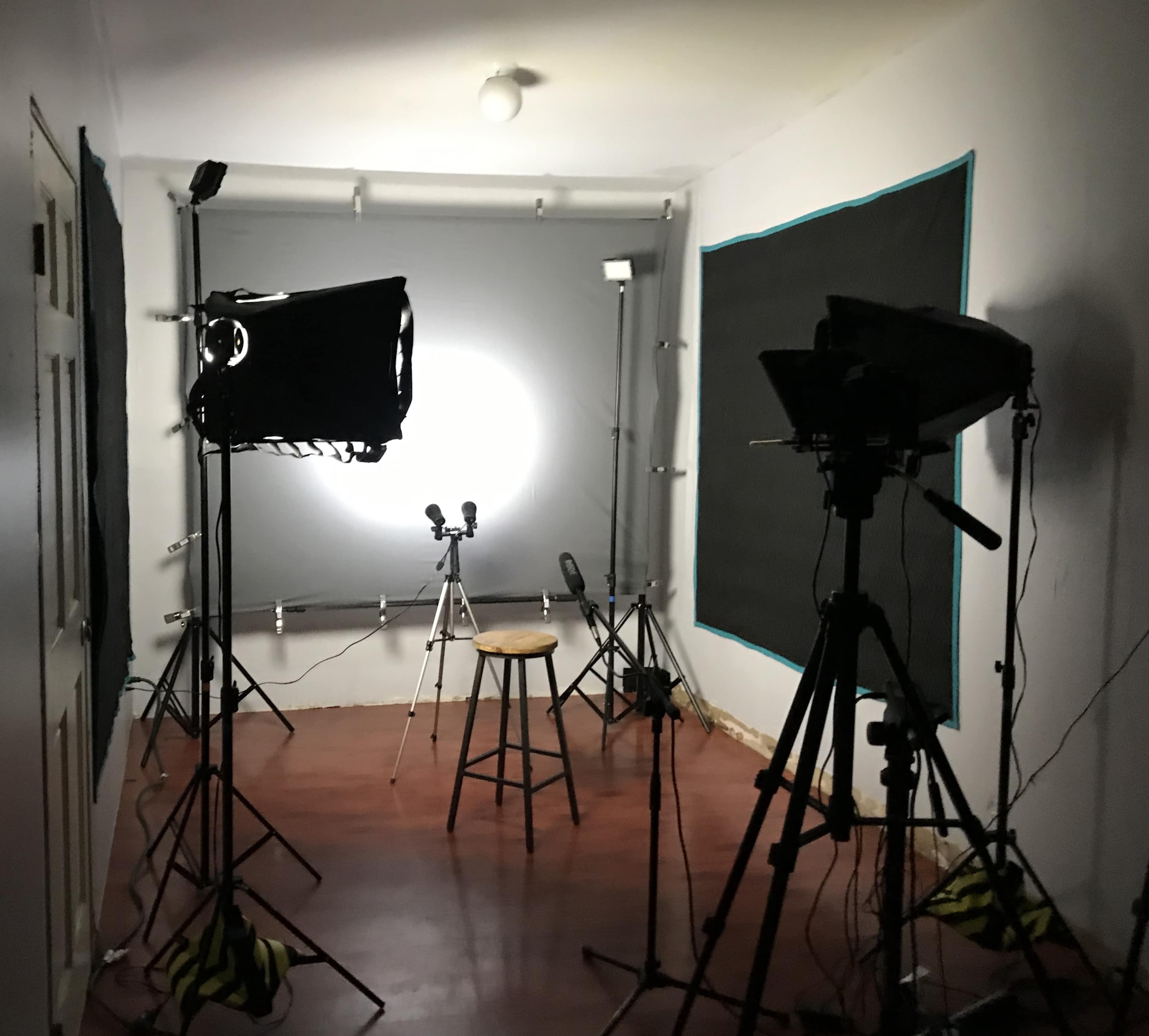 The image shows a photography studio with multiple lighting setups, a stool in the center, and a backdrop.