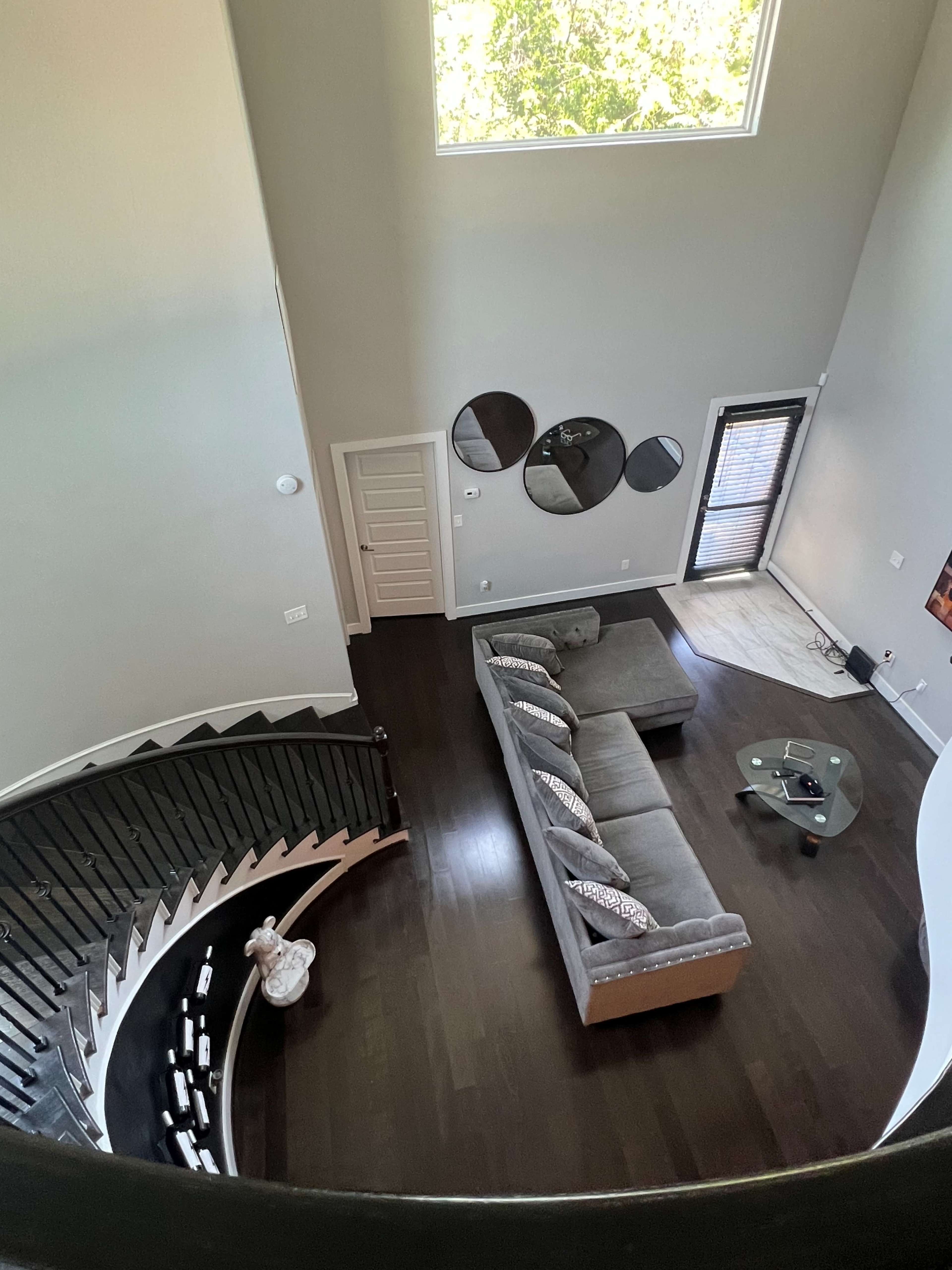 A modern living room with a sectional sofa, a coffee table, and a large window, viewed from an elevated perspective.