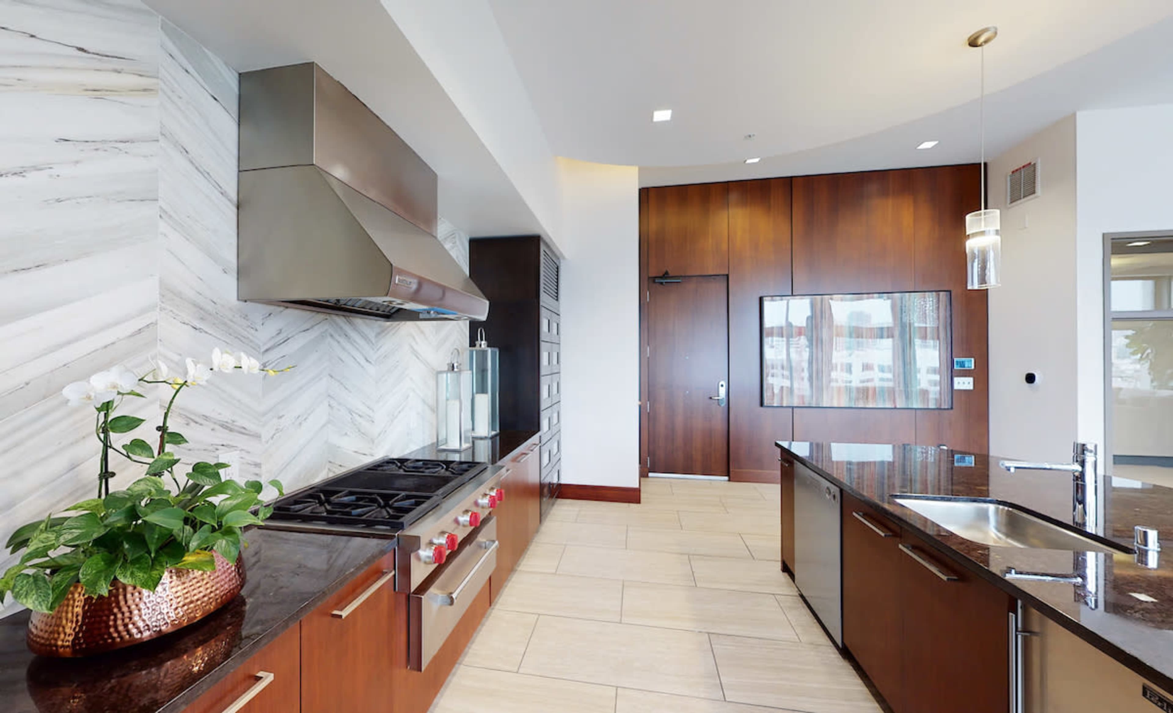 A modern kitchen featuring stainless steel appliances, dark wood cabinetry, and a large countertop.