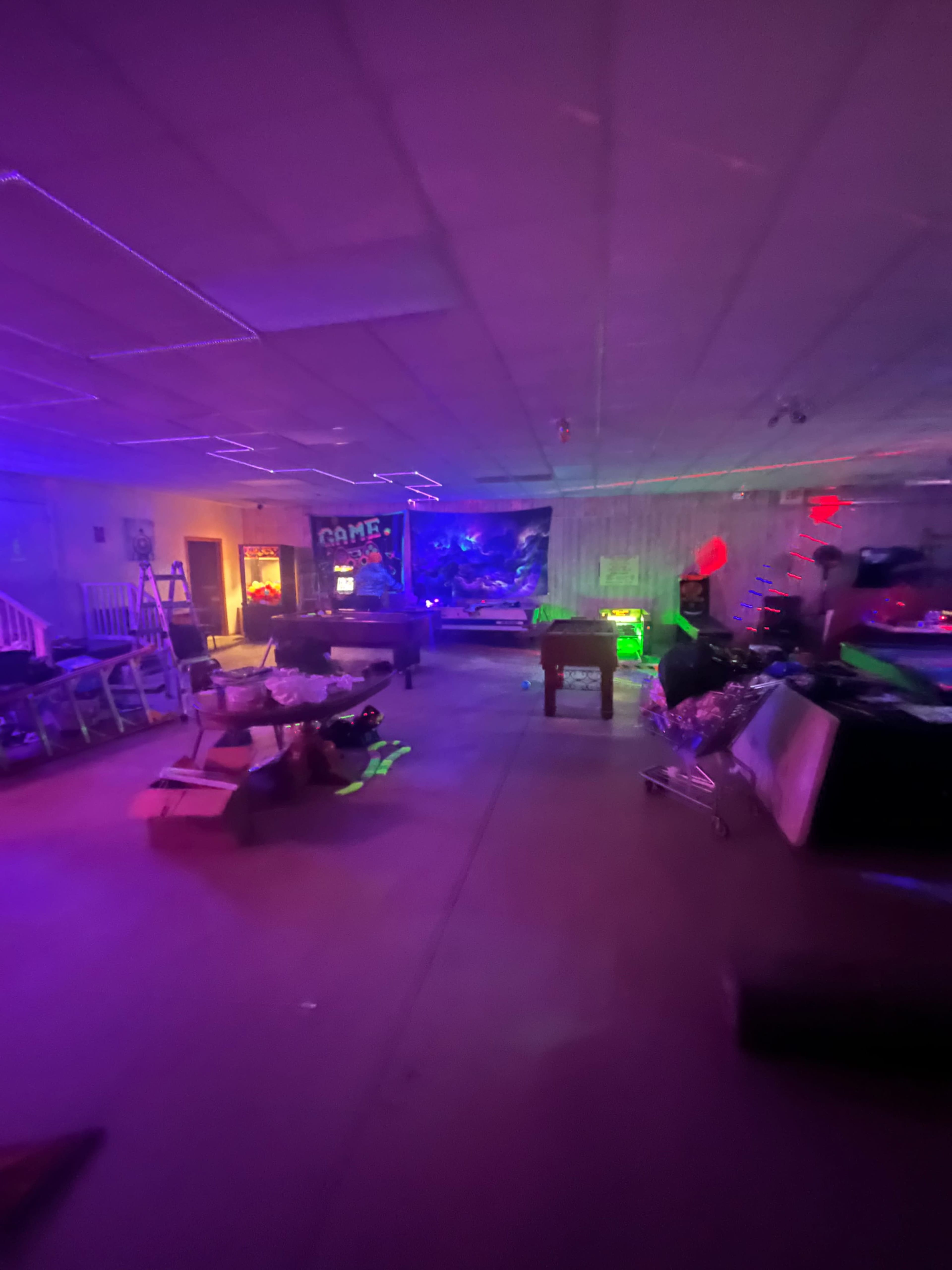 The image shows a dimly lit room with colorful lights illuminating various furniture and scattered items.