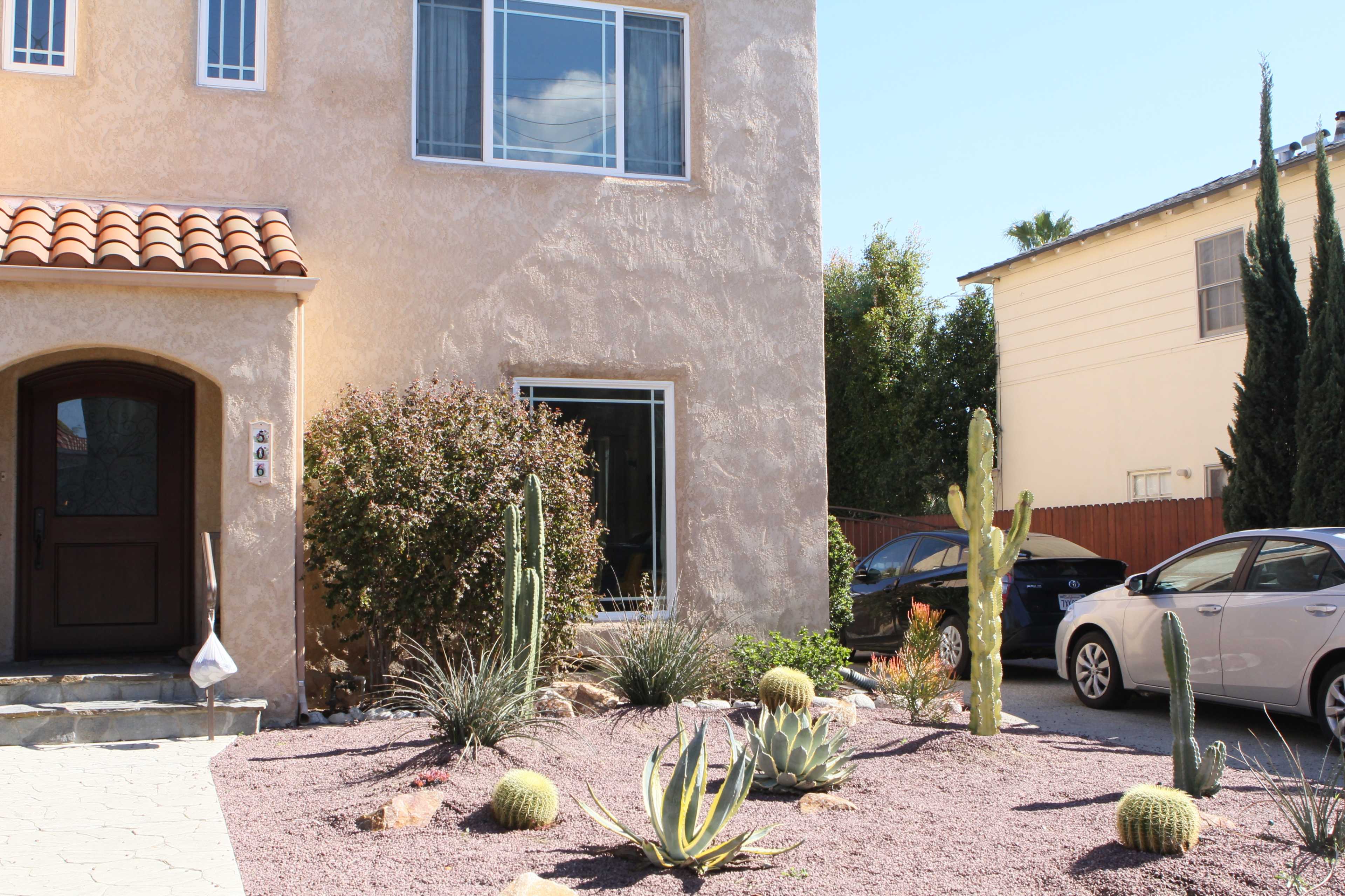 A house with a stucco exterior, featuring a landscaped front yard with various cacti and succulents on gravel.
