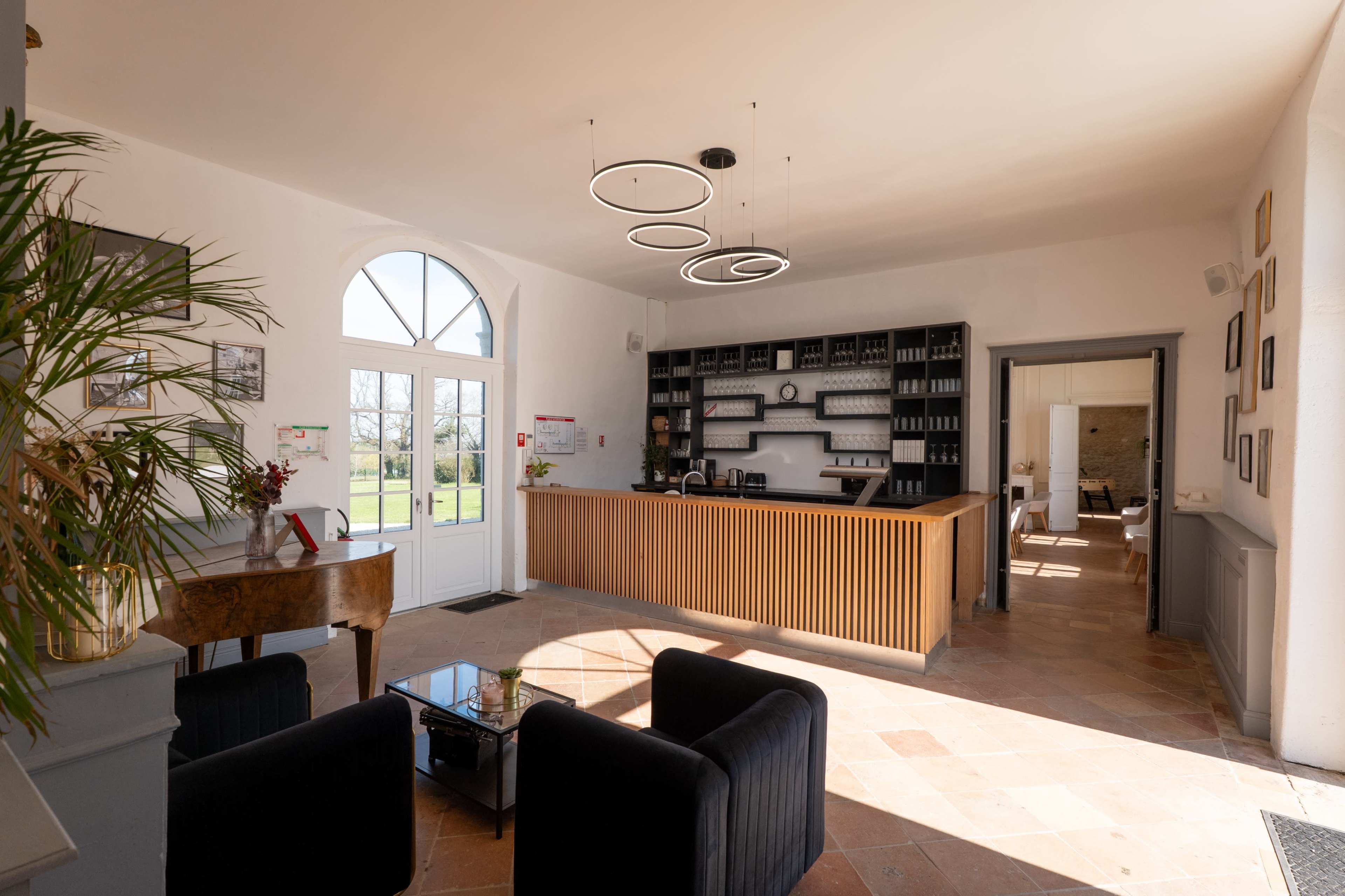The image shows a reception area with a wooden front desk, modern light fixtures, and a seating arrangement, all framed by large windows.