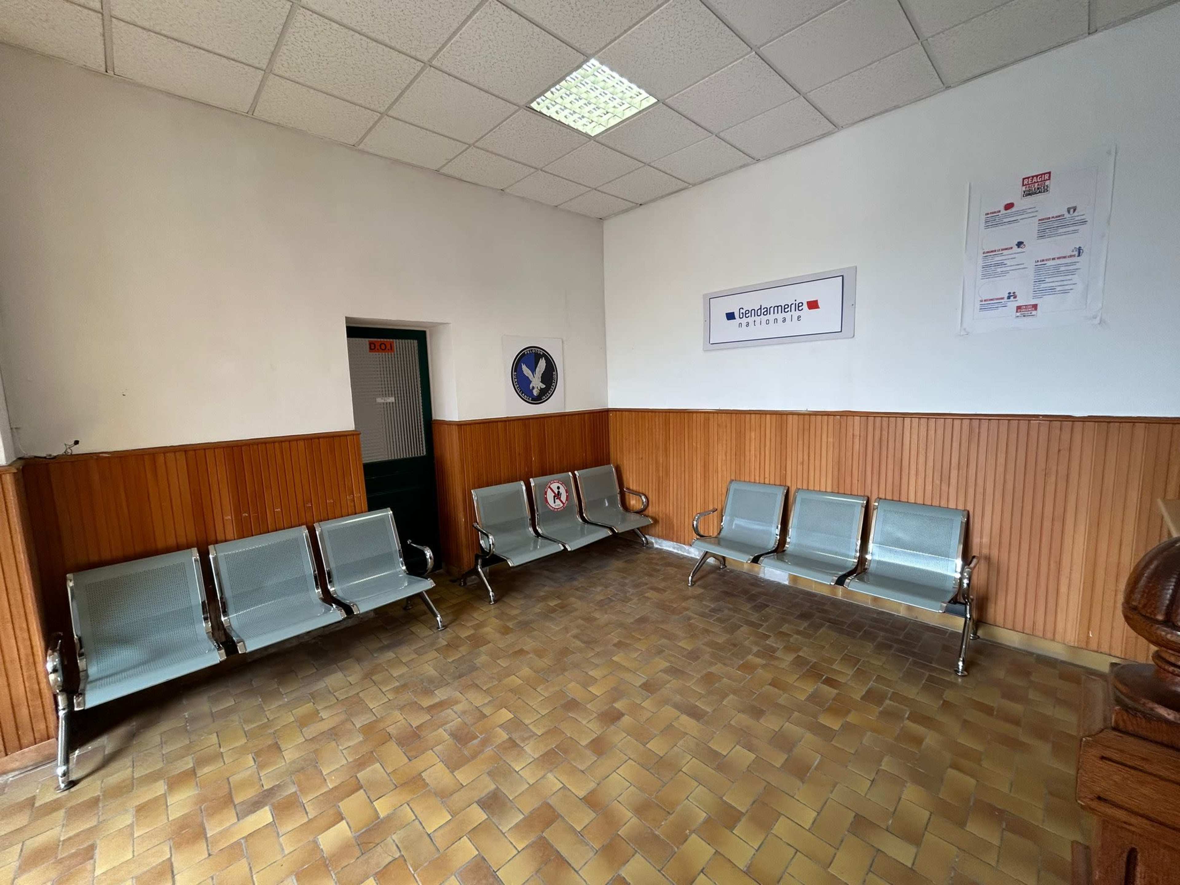 A waiting area with several metal benches and a wall displaying signs in a well-lit room.
