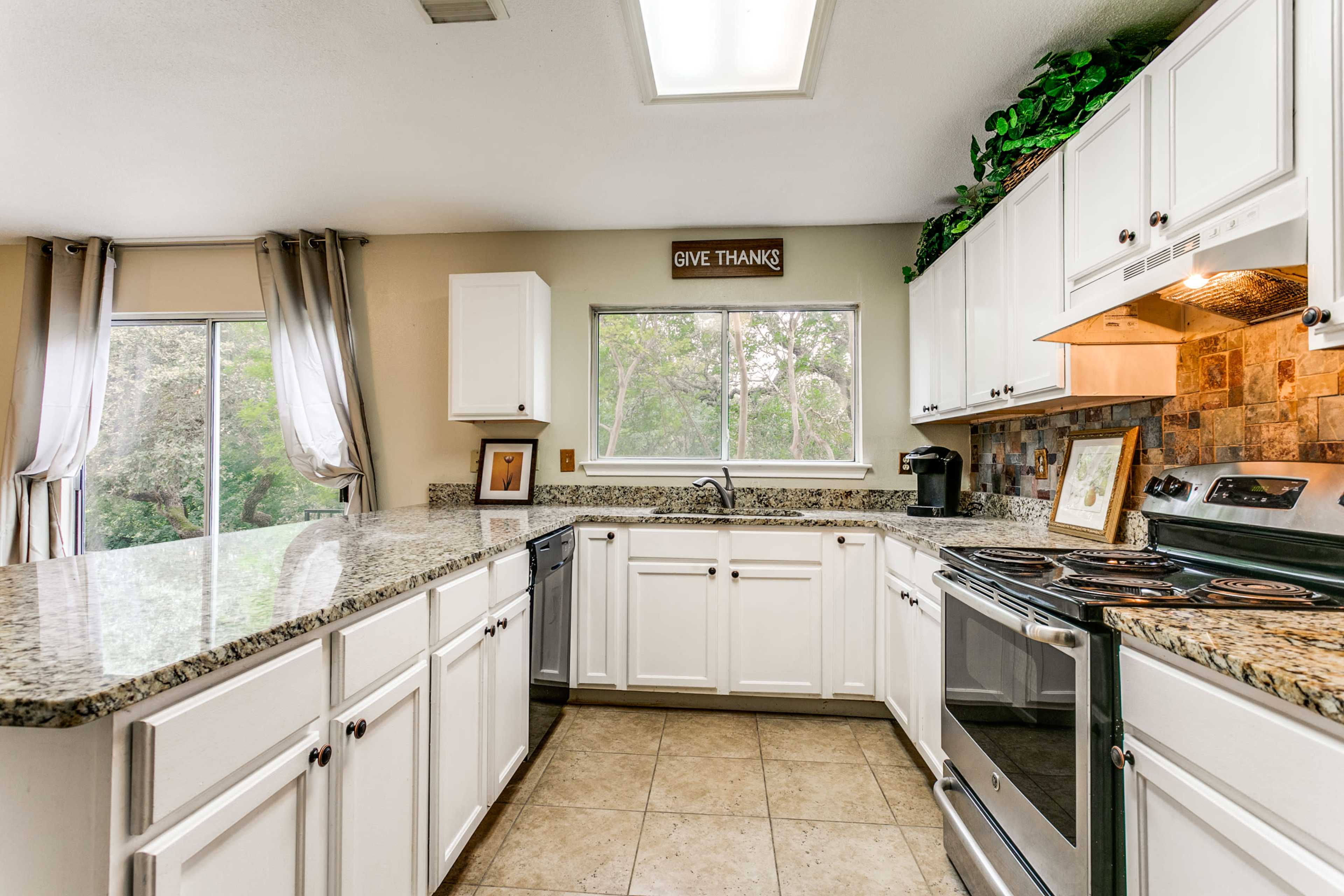 A kitchen features white cabinets, a granite countertop, and stainless steel appliances, with a window providing natural light.