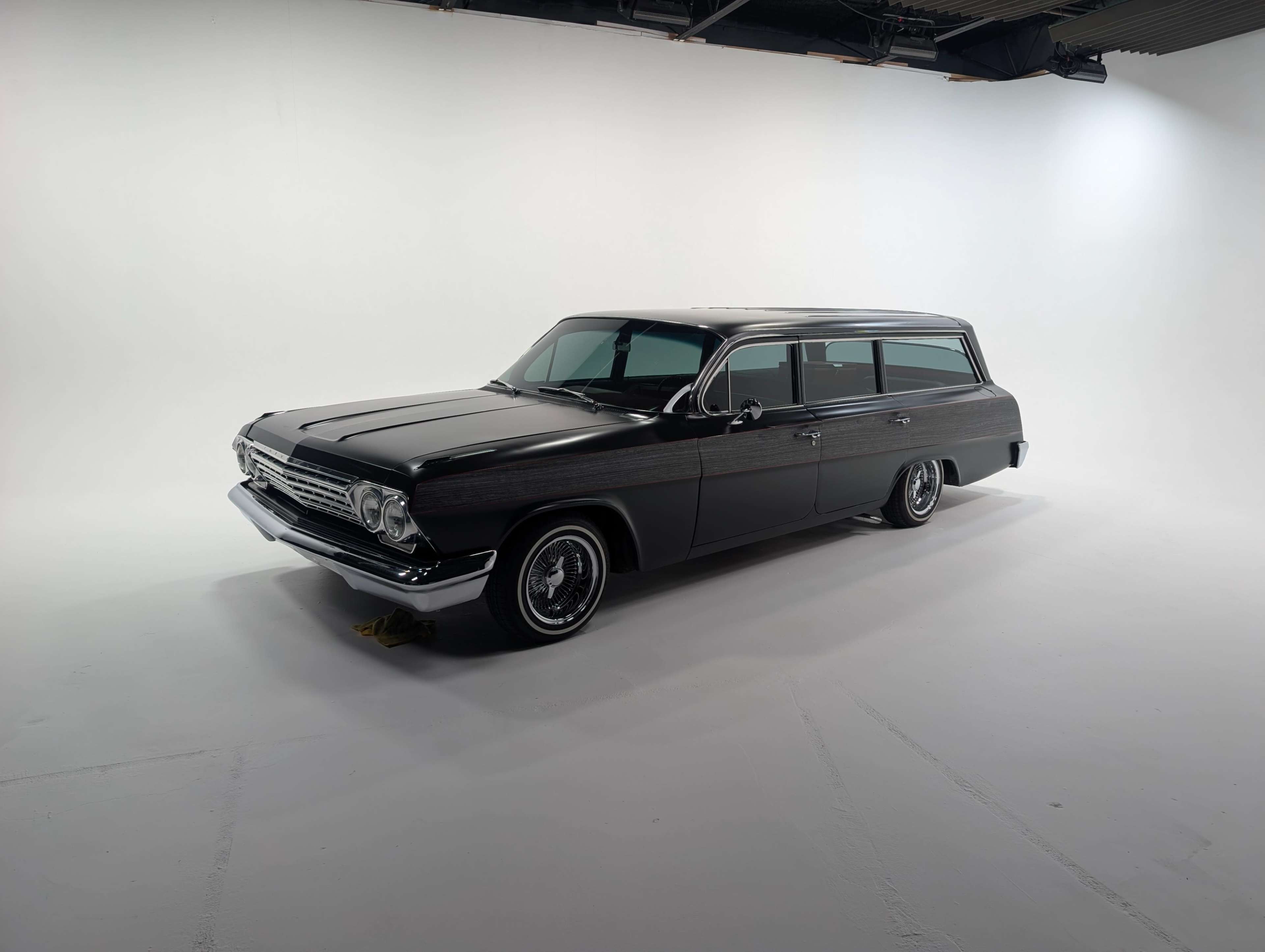 A vintage black station wagon is displayed in a well-lit studio with a plain white background.