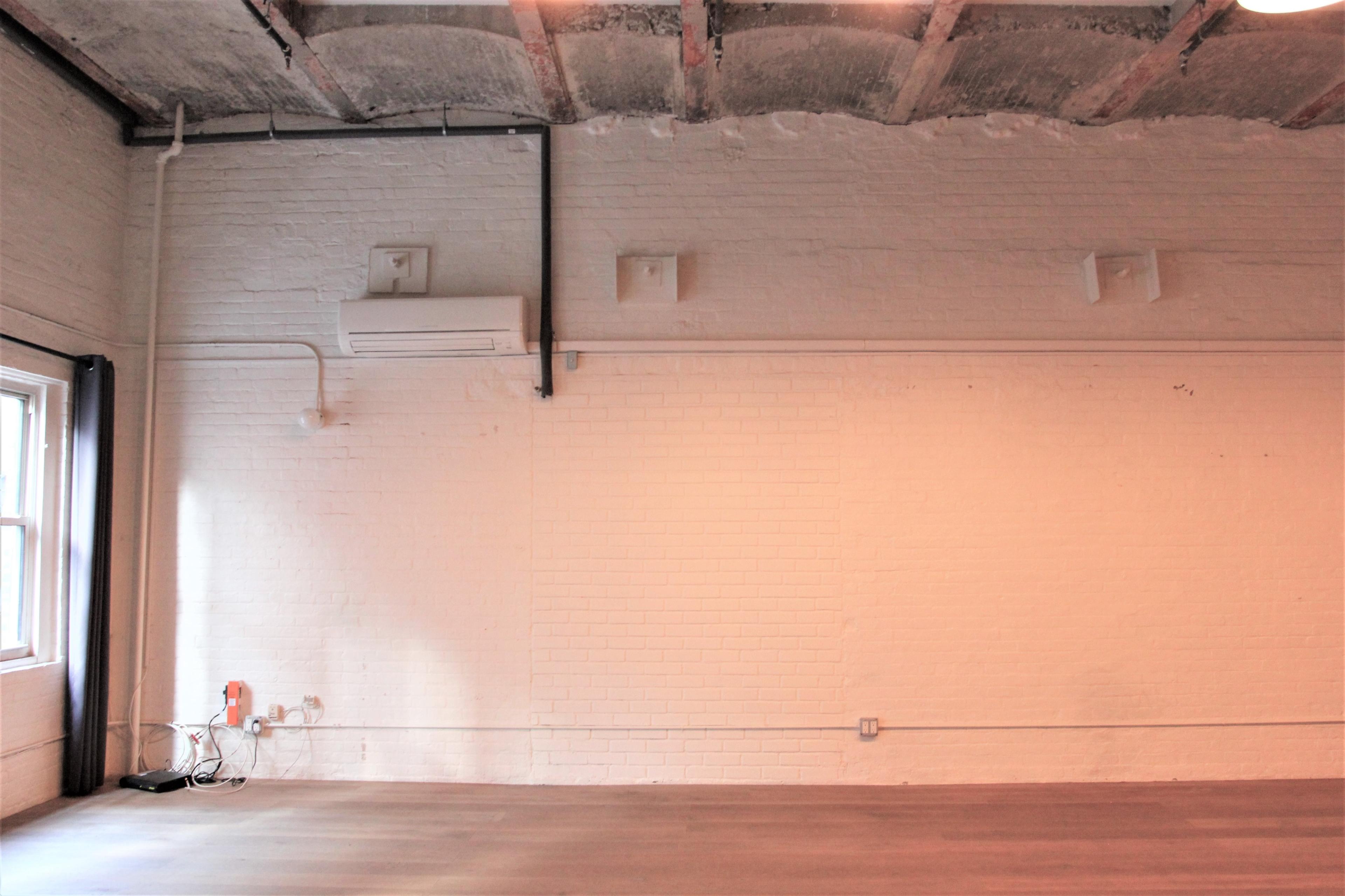 A blank interior wall with air conditioning units and exposed beams on the ceiling.