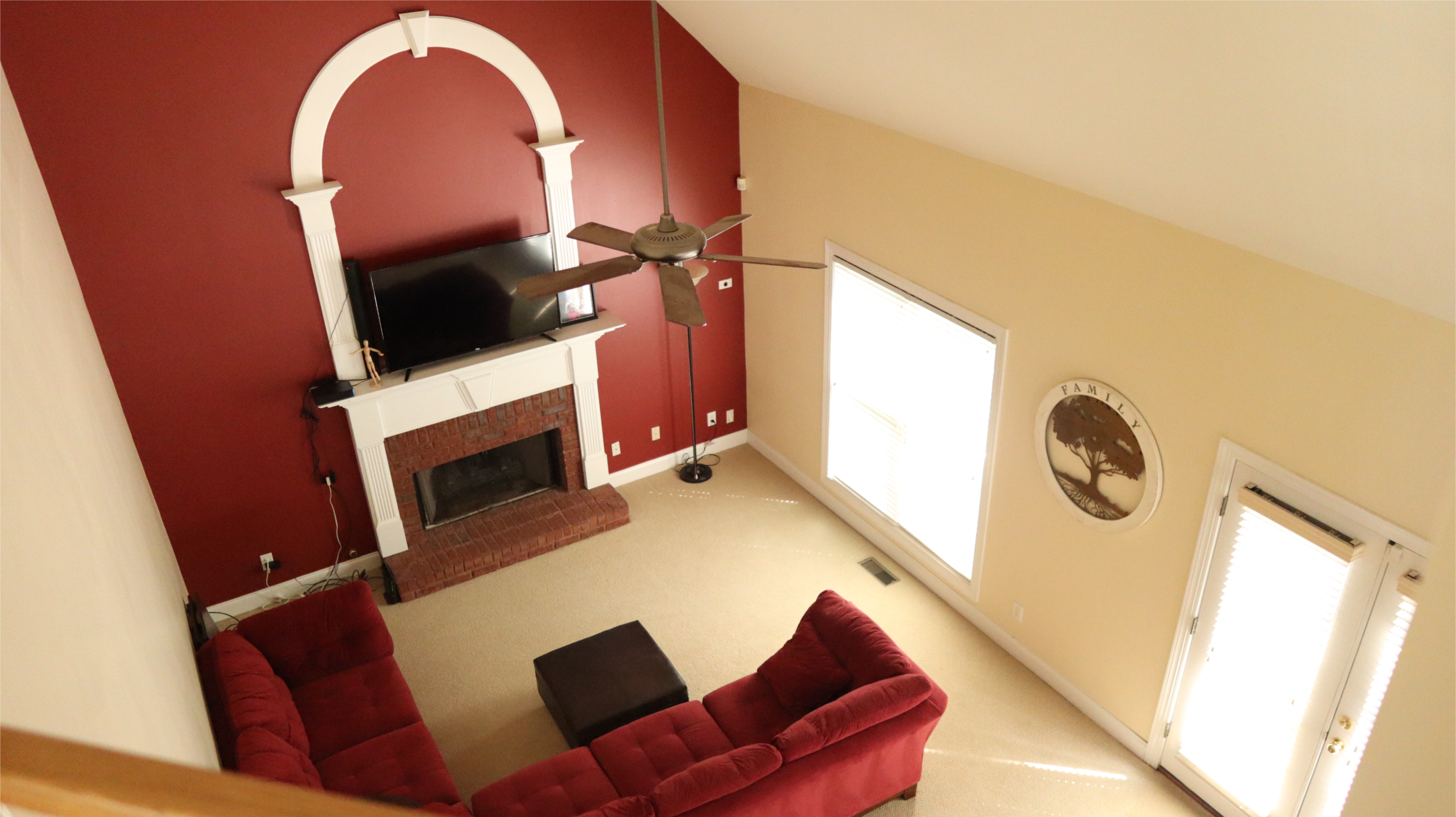 A living room with a red and beige color scheme, featuring a fireplace, a television on the mantel, and a red sectional sofa.