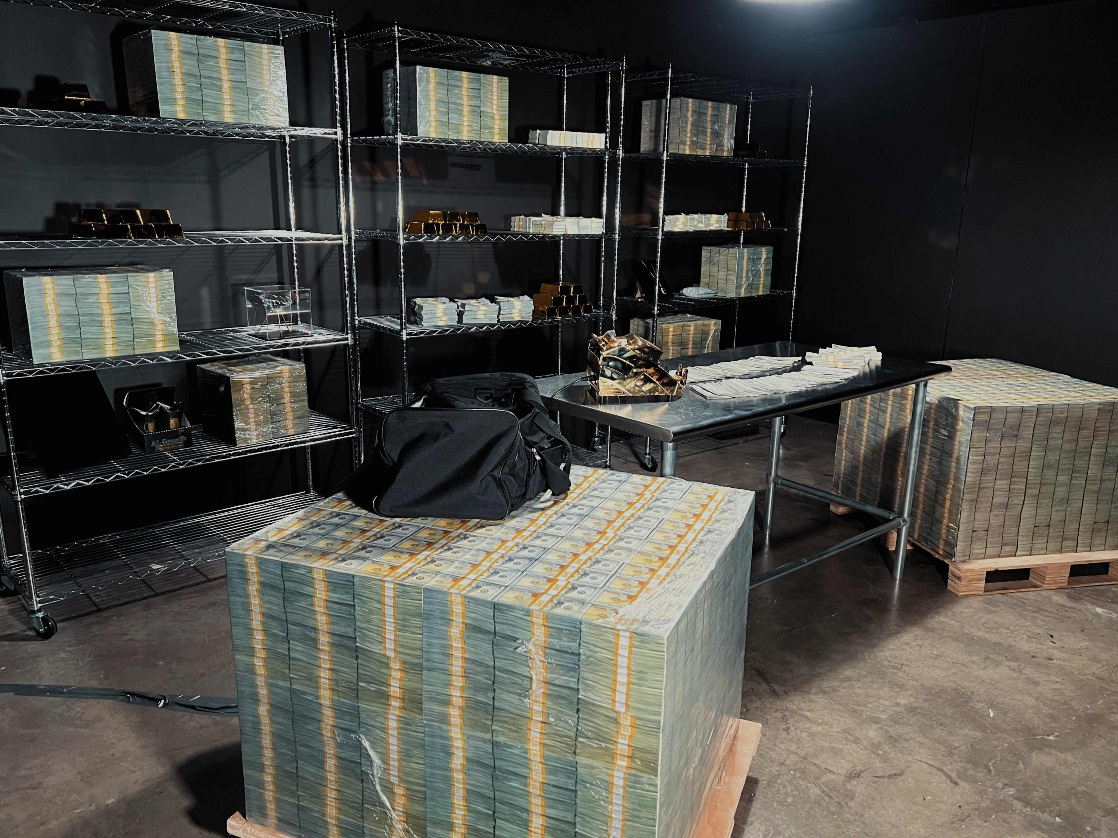 A dimly lit room with metal shelving units stacked with neatly arranged boxes and large bundles of cash on wooden pallets.