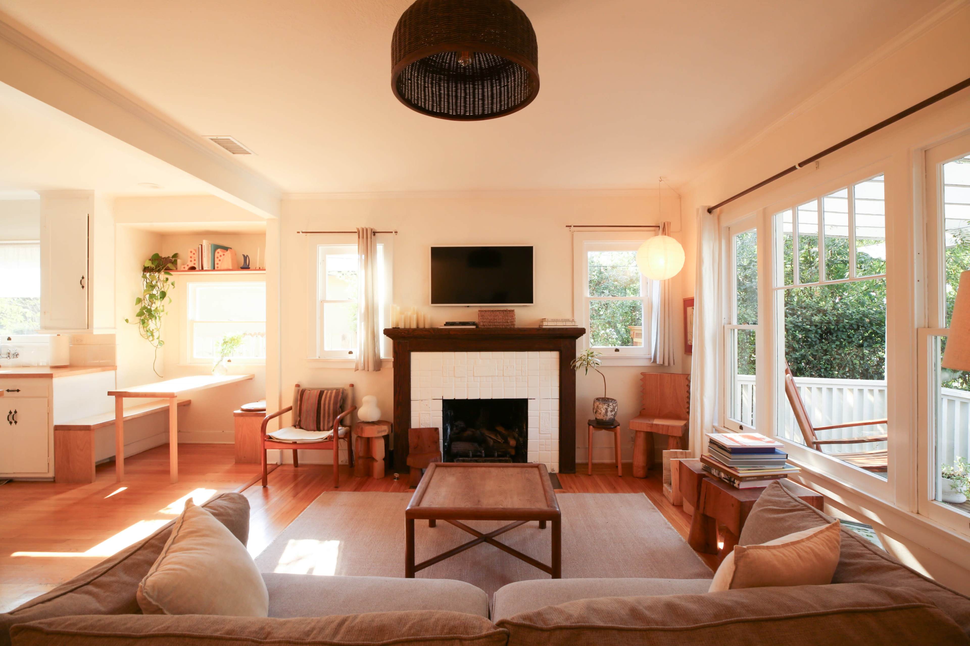 The image shows a cozy living room with a fireplace, large windows, and a seating area featuring a sofa and a coffee table.