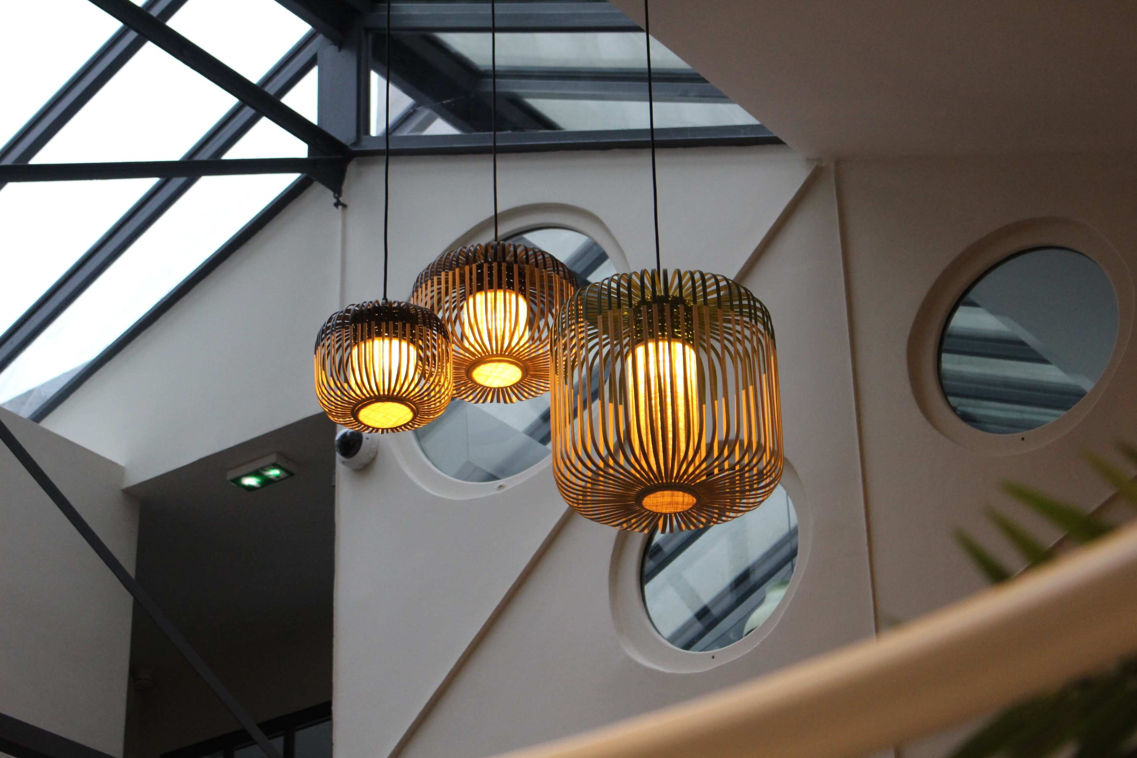 Three pendant lights with a woven design hang from the ceiling of a modern interior space.