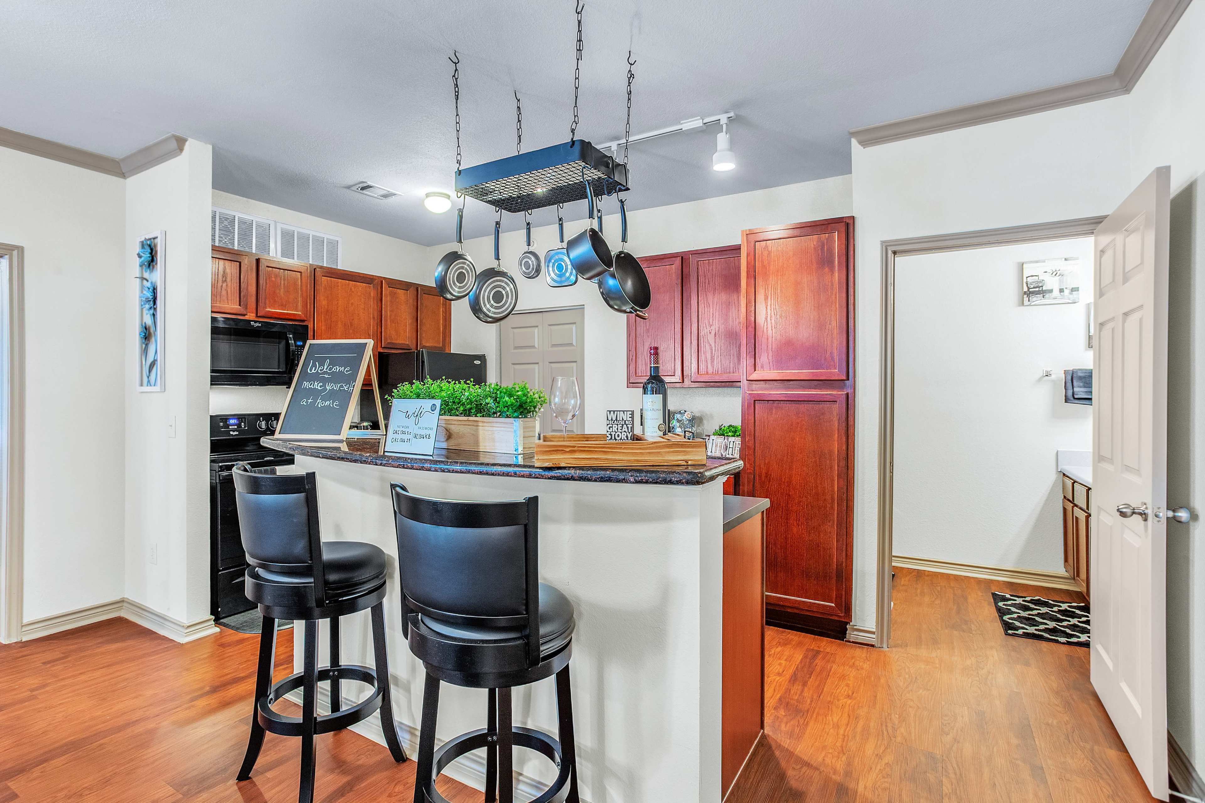 The kitchen features dark wood cabinets, a central island with bar stools, and hanging cookware above the counter.
