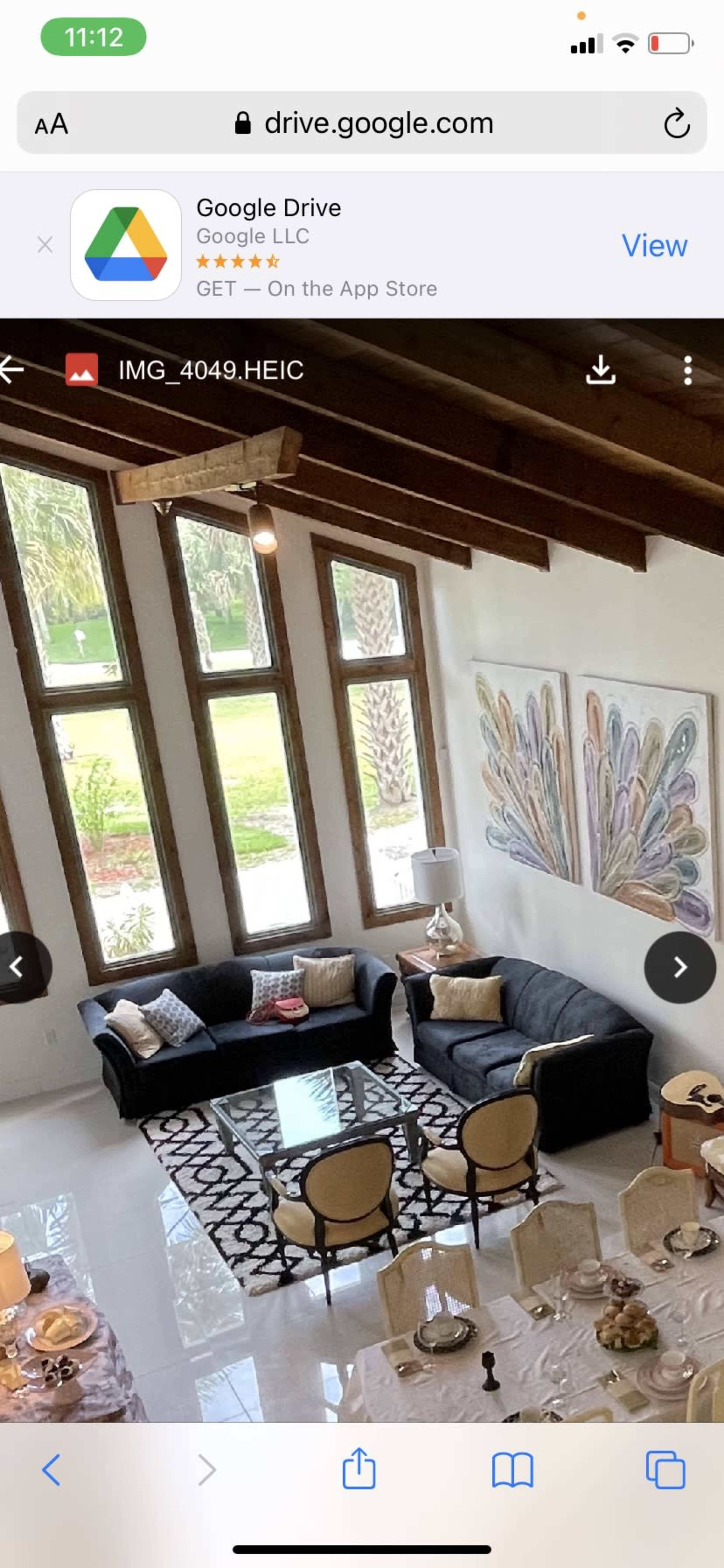 An open living space with a black sofa, a coffee table, and large windows letting in natural light.
