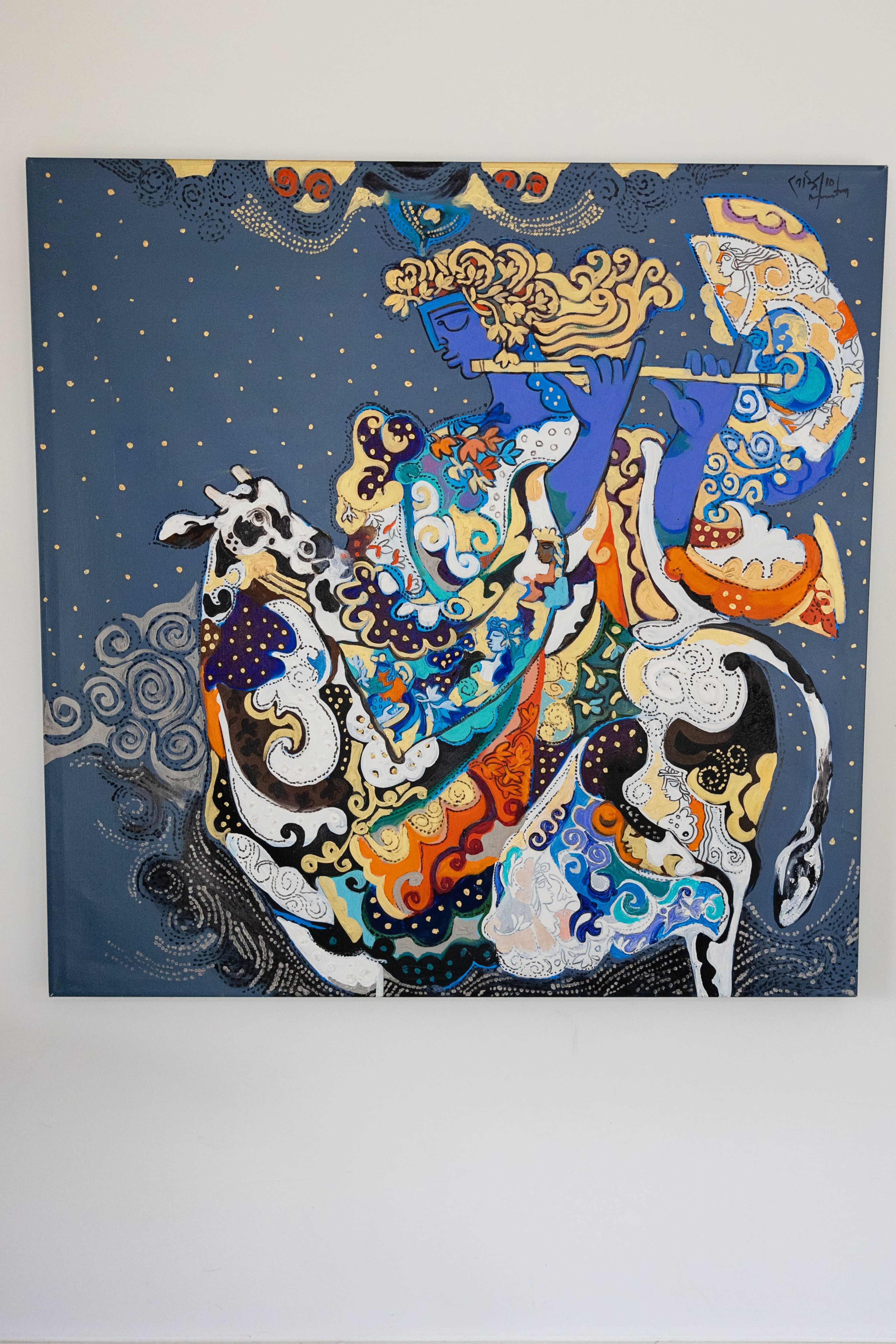 The image shows a colorful painting depicting a figure playing a flute while riding a decorated cow against a dark blue background.